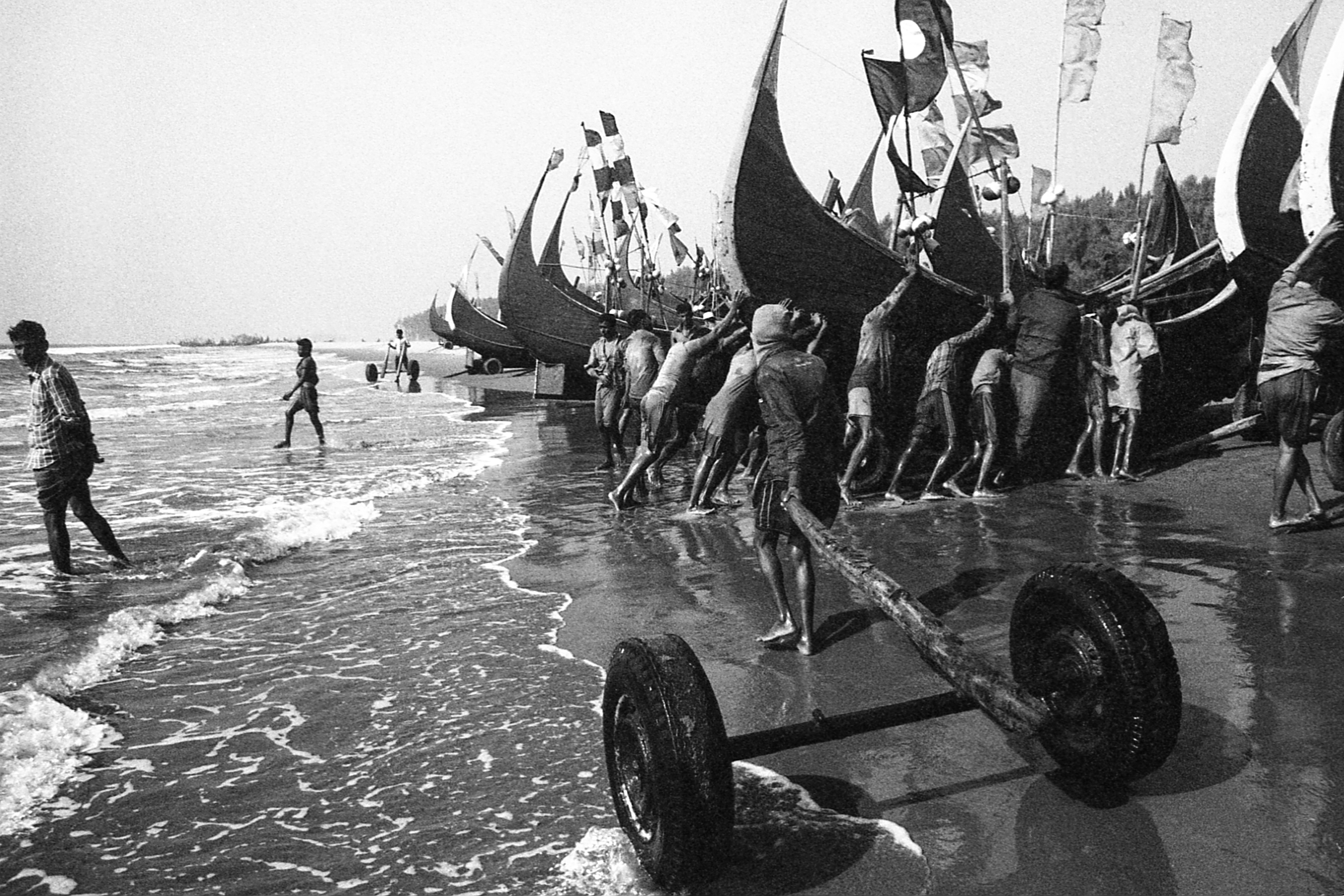 Shamlapur, Bangladesh. Each day starts and ends with a team of men shoving their fishing boats along the beach on makeshift handcarts.
