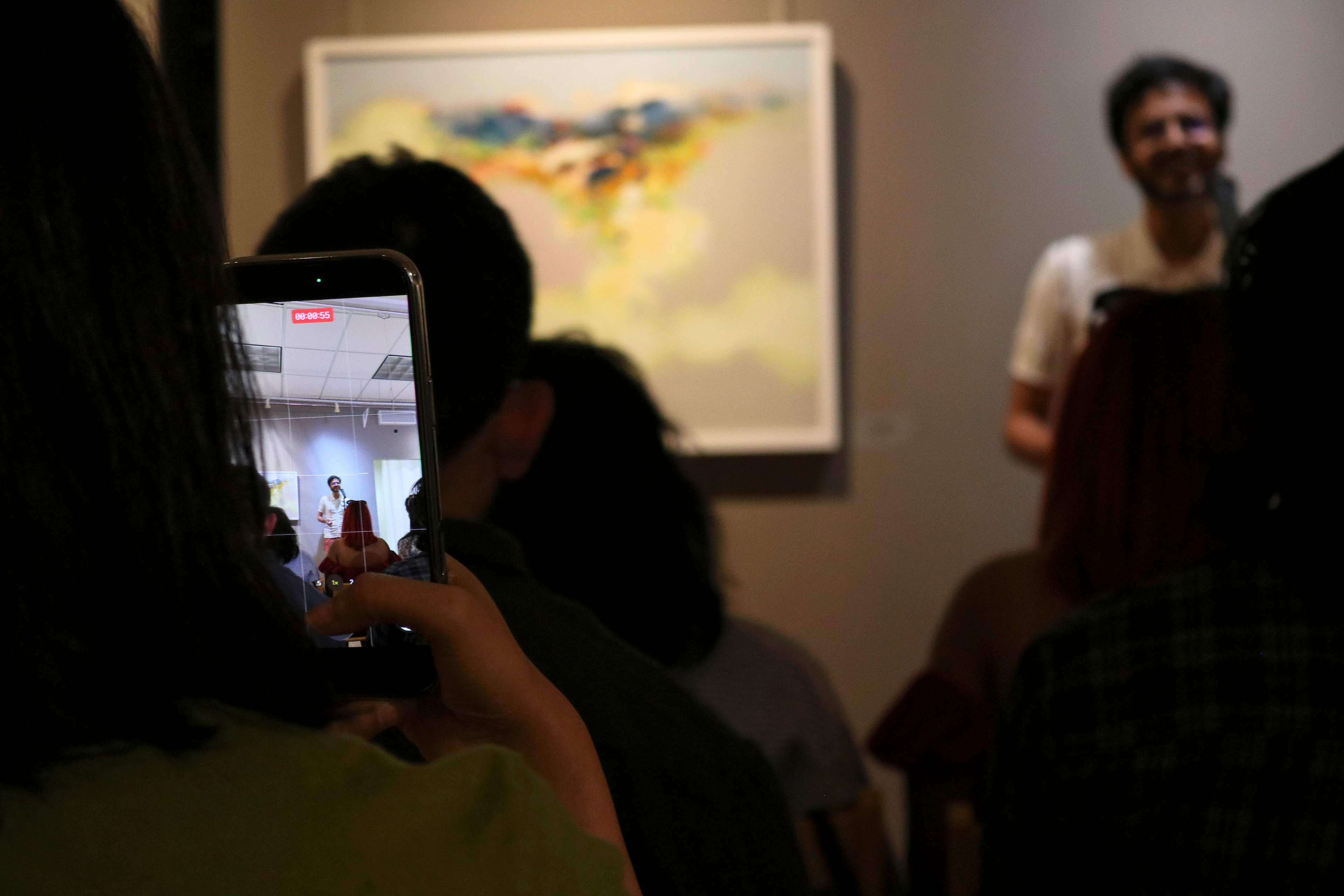 NEW BRUNSWICK, NJ 06/20/2026 CANVAS AND KAHANI: Poet Munsif Husami performs spoken word poetry to the crowd while his wife, @colorsofhoney, records him on her iPhone. Central Desi, a South Asian news publication, hosts its first-ever art showcase and open-mic at Alfa Art Gallery on Church Street. Photo by Sunah Choudhry.