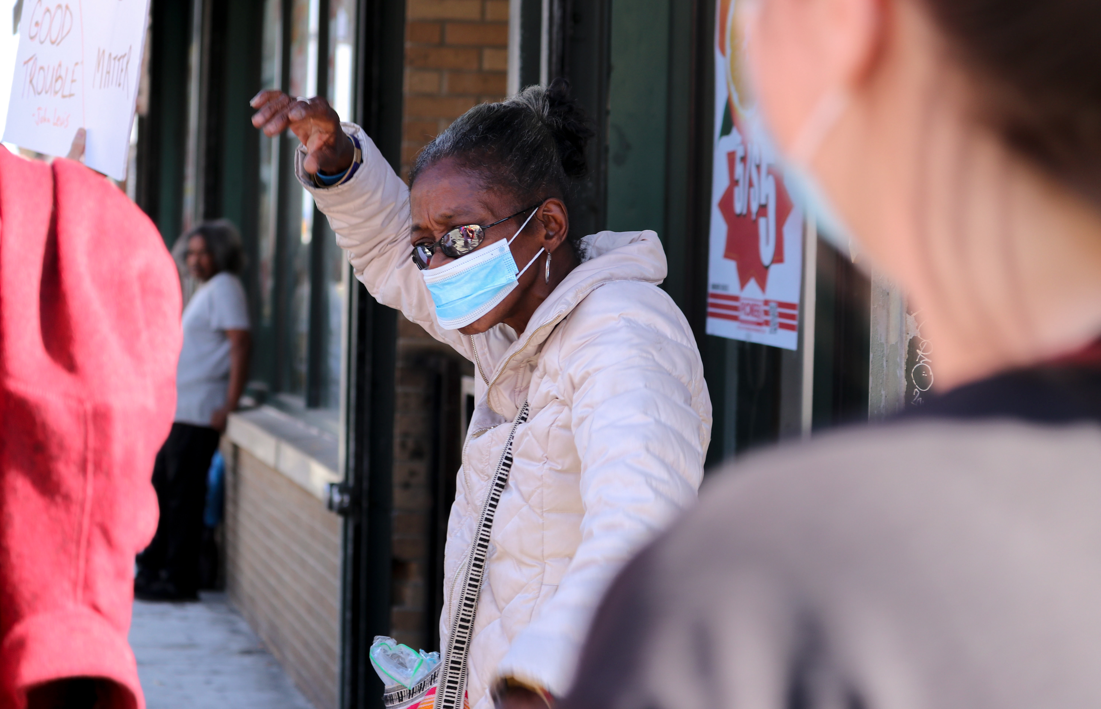 A woman cheers on protesters as they walk down the sidewalk. (Photo/Sunah Choudhry)