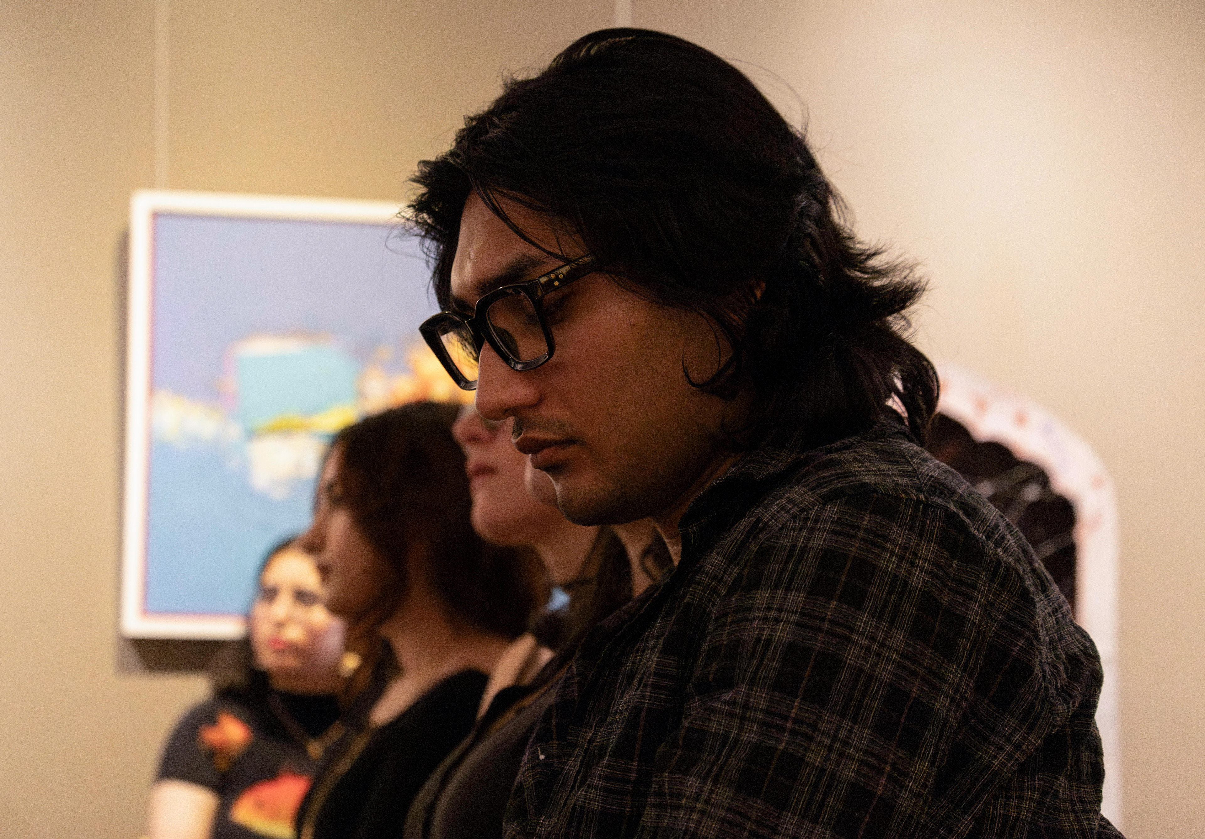 NEW BRUNSWICK, NJ 06/20/2026 CANVAS AND KAHANI: An attendee of Canvas and Kahani listens to poet Munsif Husami. Central Desi, a South Asian news publication, hosts its first-ever art showcase and open-mic at Alfa Art Gallery on Church Street. Photo by Sunah Choudhry.