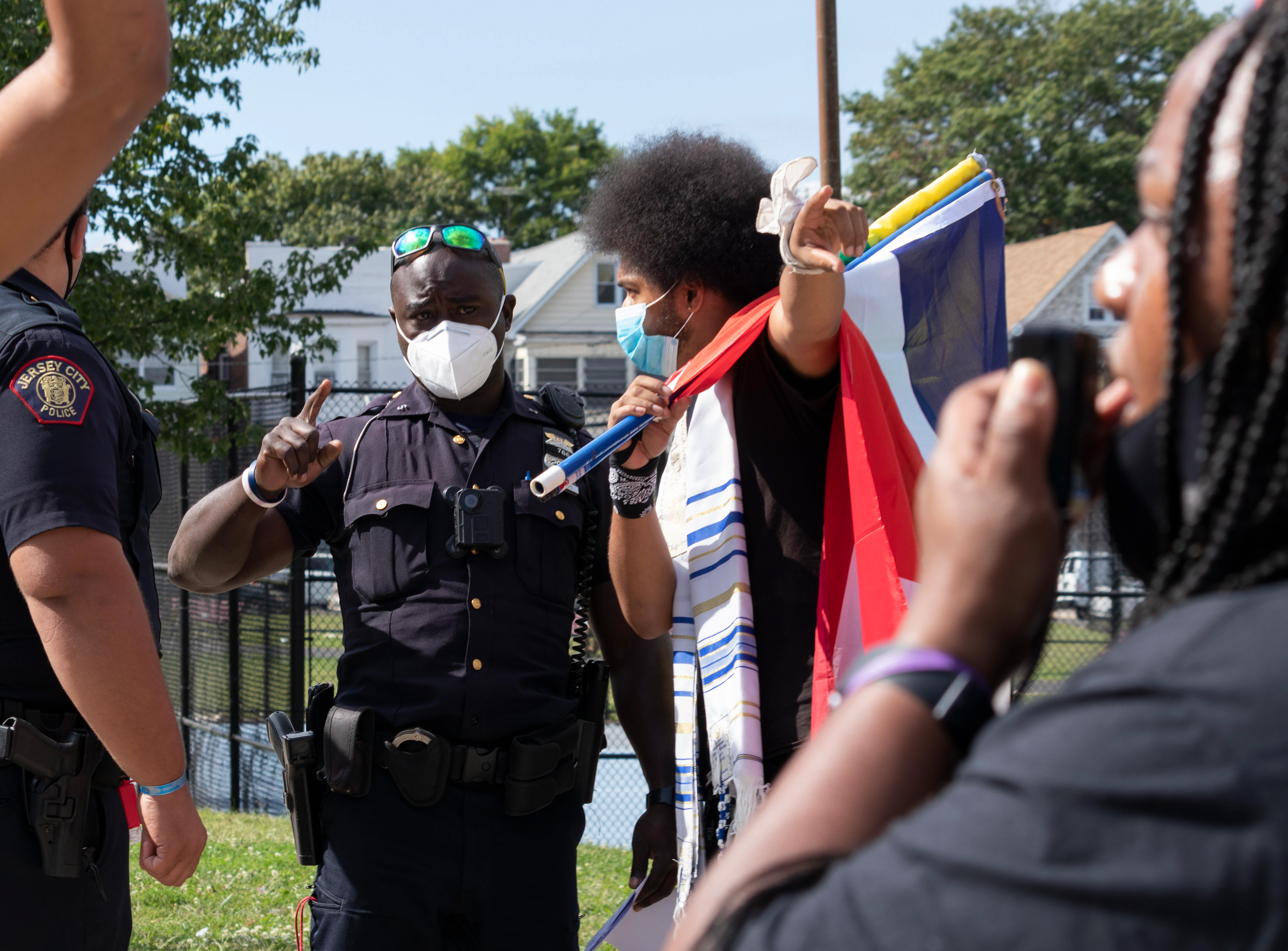 Rostafa speaks with a Jersey City police officer before intiating the protest to Berry Land Park.
