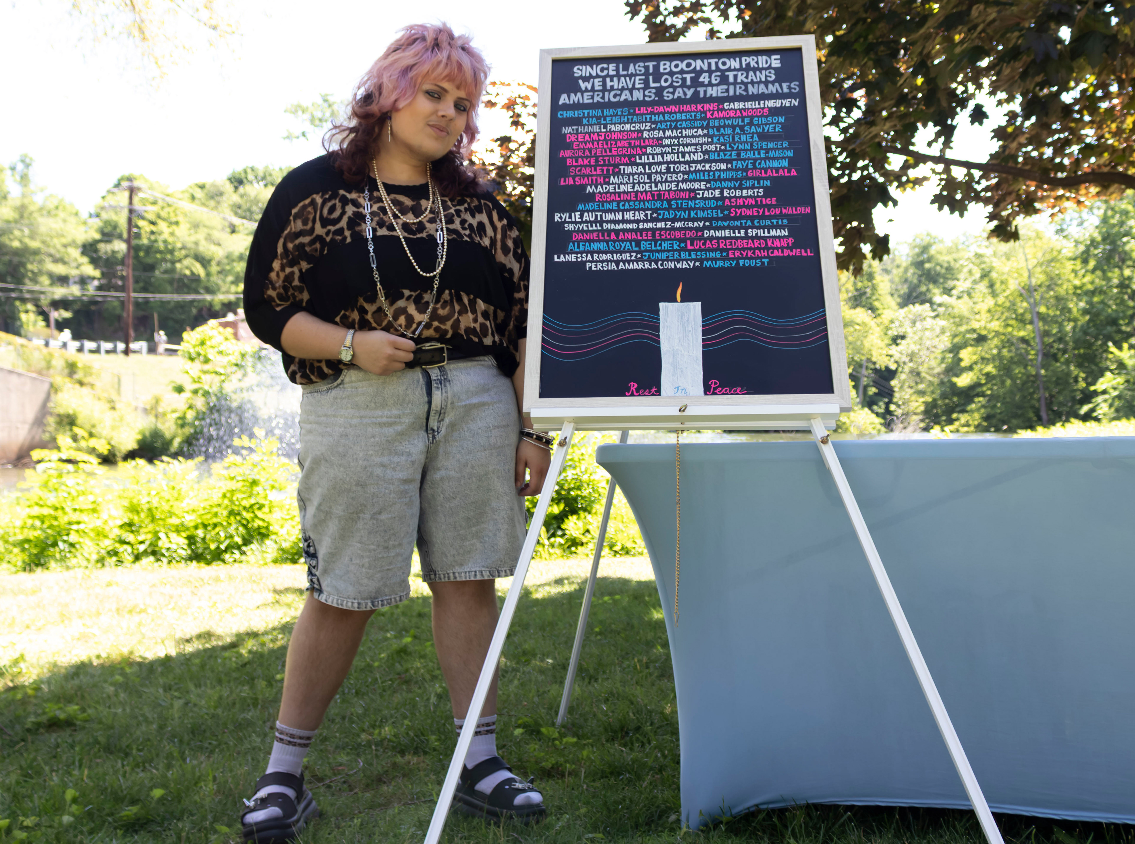 BOONTON, NJ 06/20/2026 BOONTON PRIDE AT GRACE LORD PARK: Performer and artist Vincent Jude stands beside an artwork documenting lives lost since Boonton’s 2025 Pride celebration. Boonton residents and visitors gather to celebrate Pride, hear from speakers and watch performances by the Mayo Performing Arts Company.
