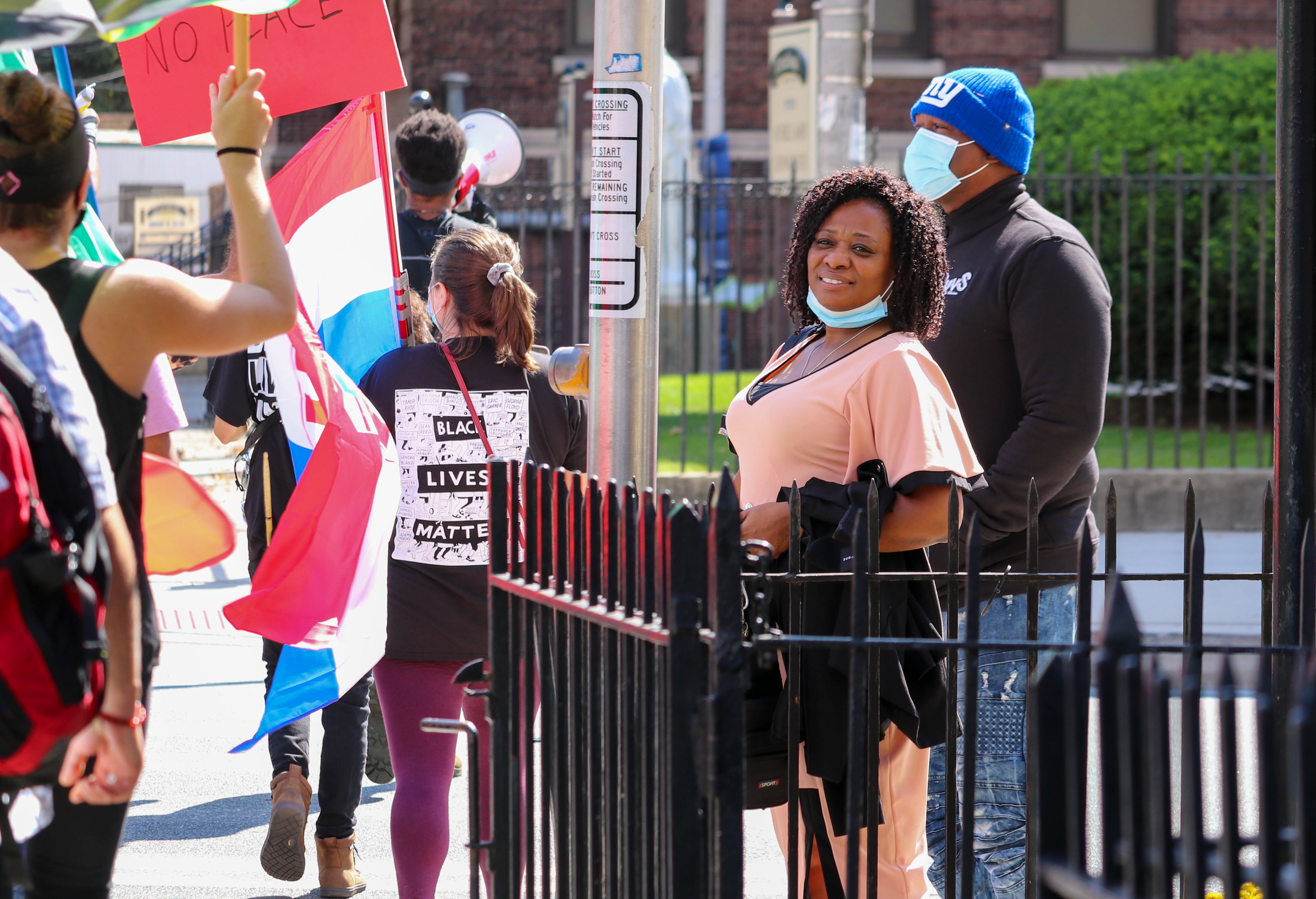 A couple admires protesters as they walk down the sidewalk. (Photo/Sunah Choudhry)
