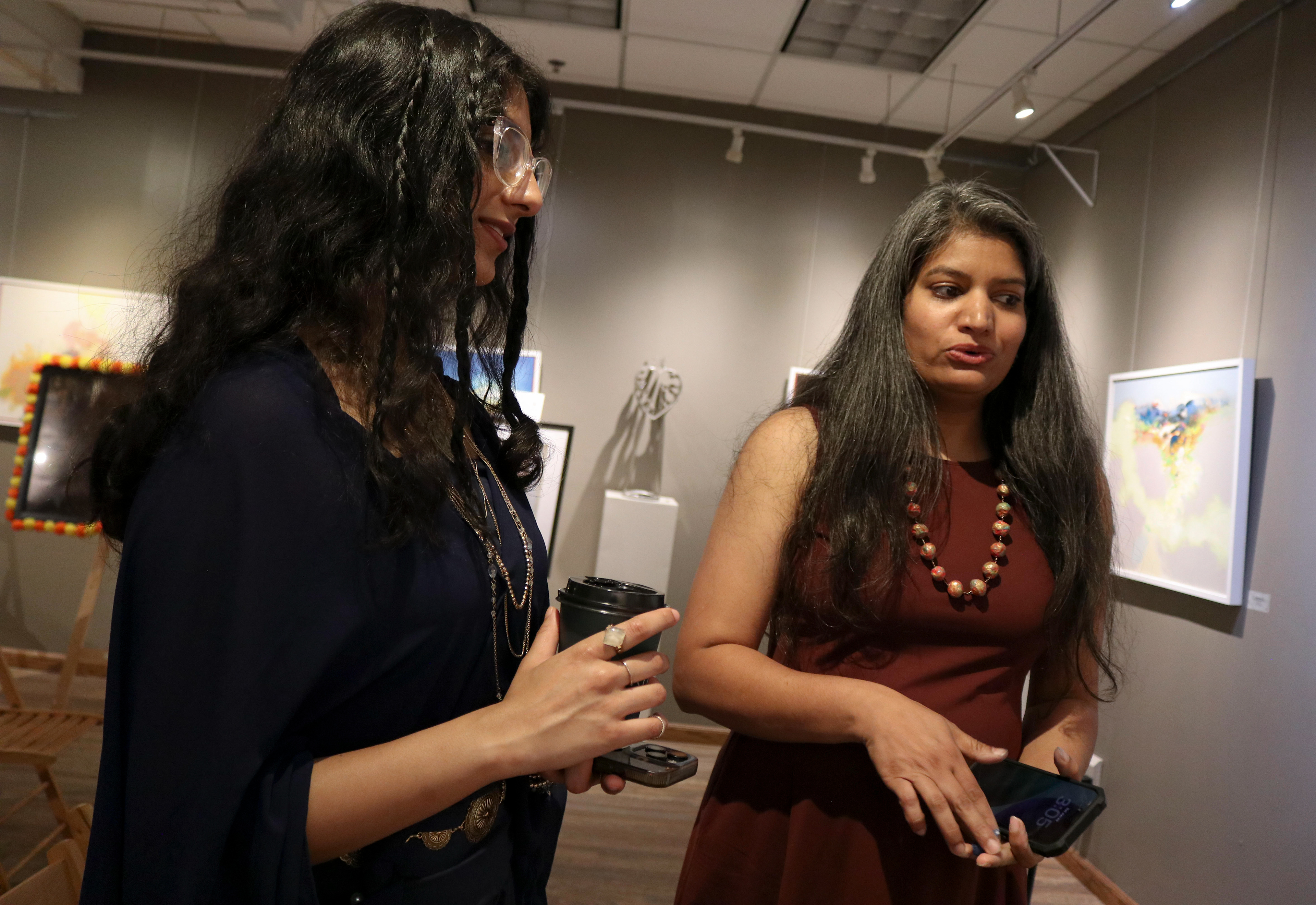 NEW BRUNSWICK, NJ 06/20/2026 CANVAS AND KAHANI: Pyrographist Janhavi Firke discusses her wood-burning masterpiece, “Life in Motion,” with Mommina. The piece displays that life is never-ending and a constant circle of evolution. Central Desi, a South Asian news publication, hosts its first-ever art showcase and open-mic at Alfa Art Gallery on Church Street. Photo by Sunah Choudhry.