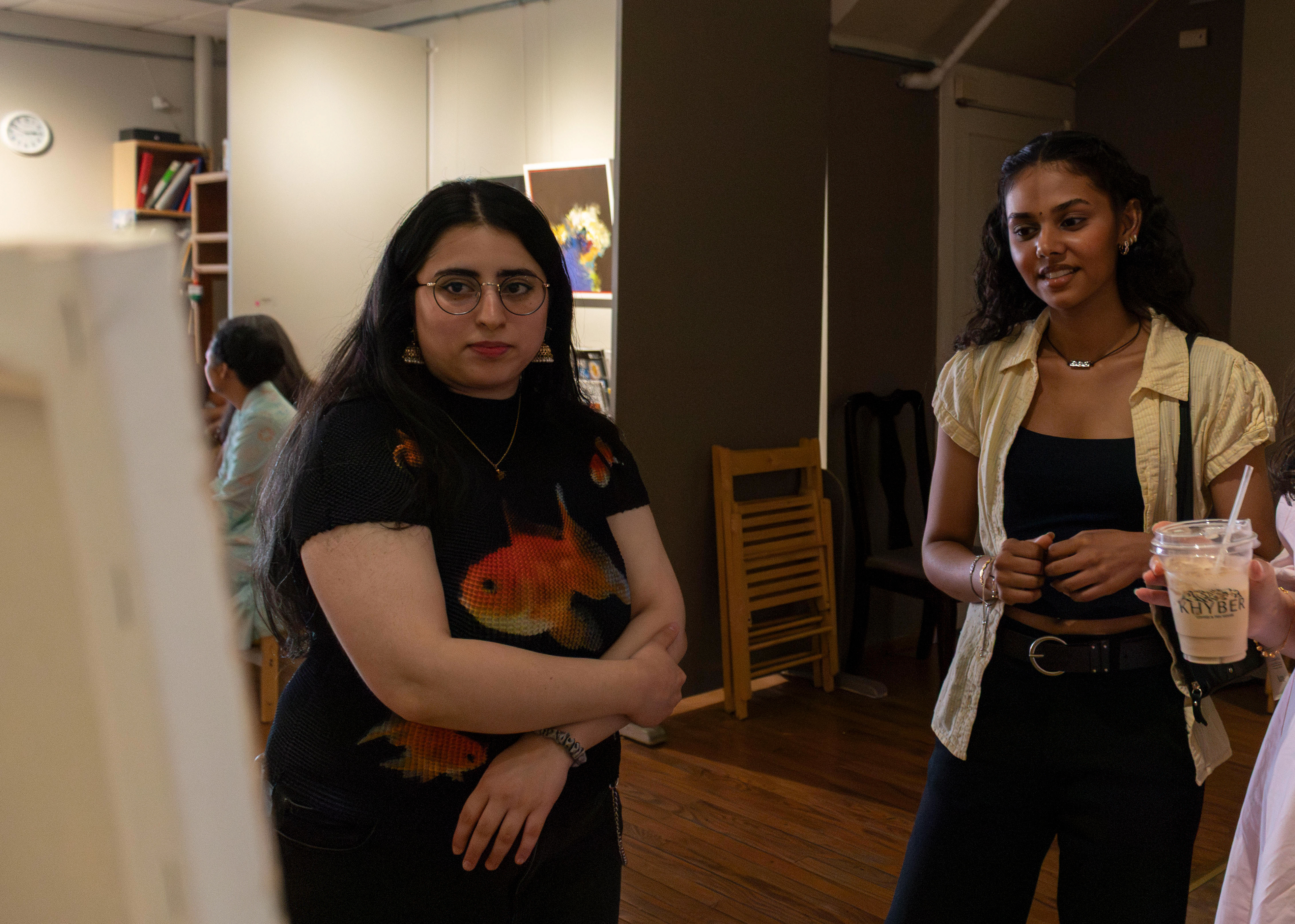 NEW BRUNSWICK, NJ 06/20/2026 CANVAS AND KAHANI: Ifrah Akhtar, Associate Editor of Central Desi, and Artist and Rutgers alumna Rushiga Sarveiya observe and talk about Zainab Masoud’s piece, “Techno-Feudalism.” Central Desi, a South Asian news publication, hosts its first-ever art showcase and open-mic at Alfa Art Gallery on Church Street. Photo by Sunah Choudhry.