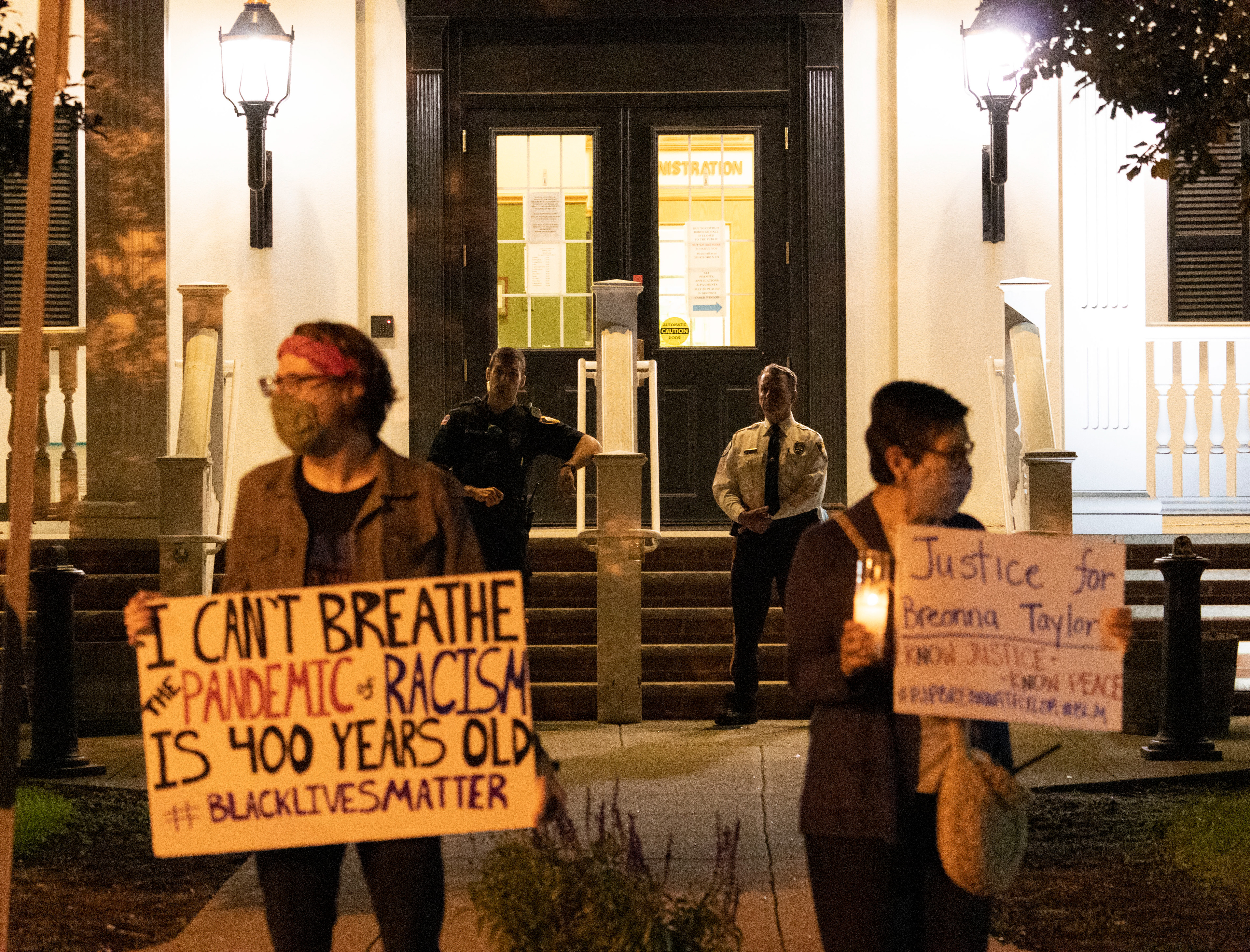 RAMSEY, NJ 09/24/2020 RASE TOWN HALL PHONE IN: Leader and organizer of Ramsey Alliance for Social Equity (RASE) Nick Haas (left) and Instagram live stream coordinator Jennifer Sauer protest outside of Ramsey Town Hall during a phone call in to propose a diversity and inclusion committee to advise the council on issues of social justice. Behind them is Ramsey Chief of Police Bryan Gurney and an unidentified police officer. (Photo/Sunah Choudhry)
