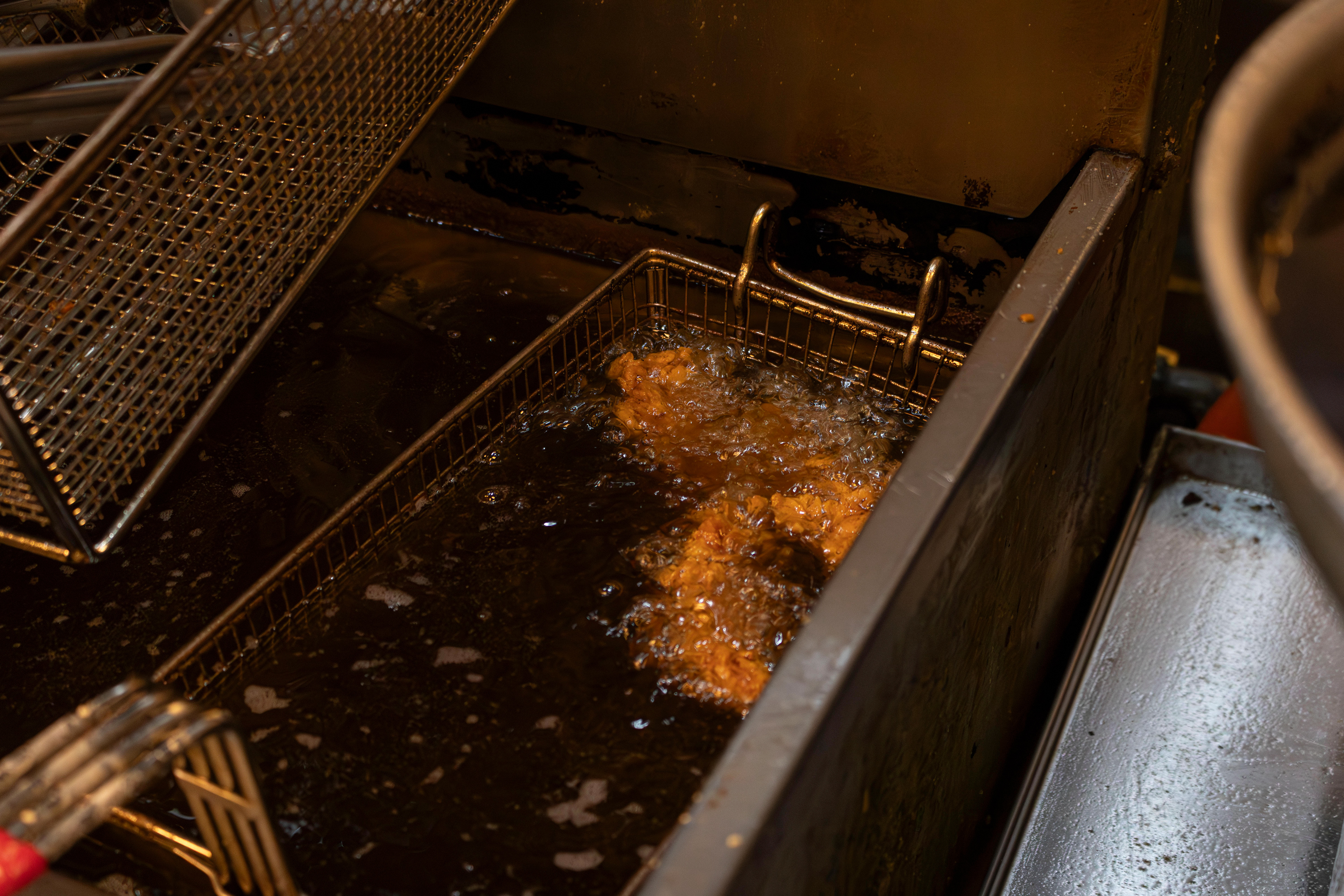 Chicken fries in canola oil to prepare a fried chicken sandwich in Food Street's kitchen. Photo by Sunah Choudhry.