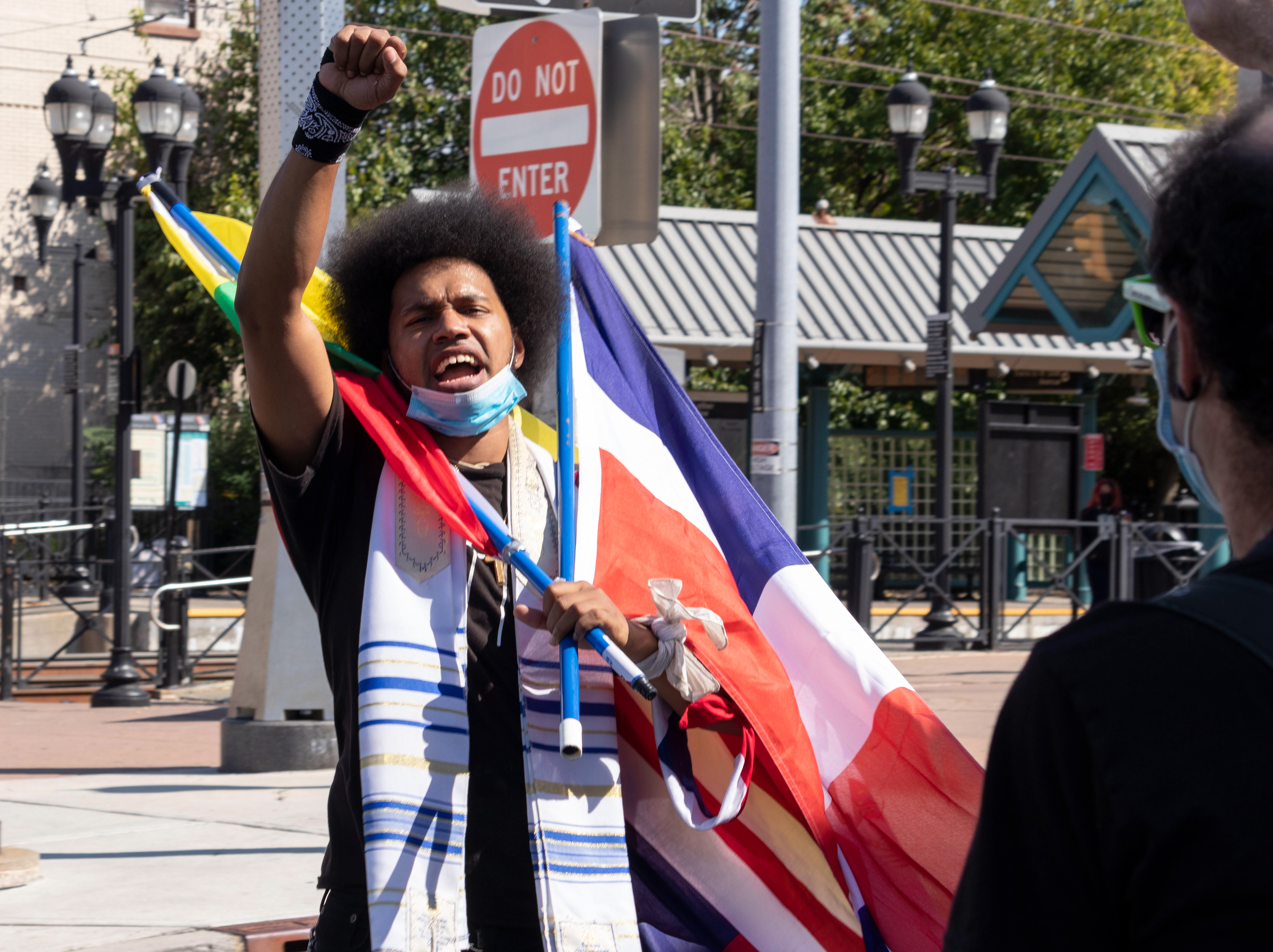 West Orange native Rostafa leads the march, holding two flags and holding his fist in the air. The march starts from Audobon Park and ends at Berry Lane Park where the first Kemet Festival is being held which includes speakers, music, and vendors. (Photo/Sunah Choudhry)