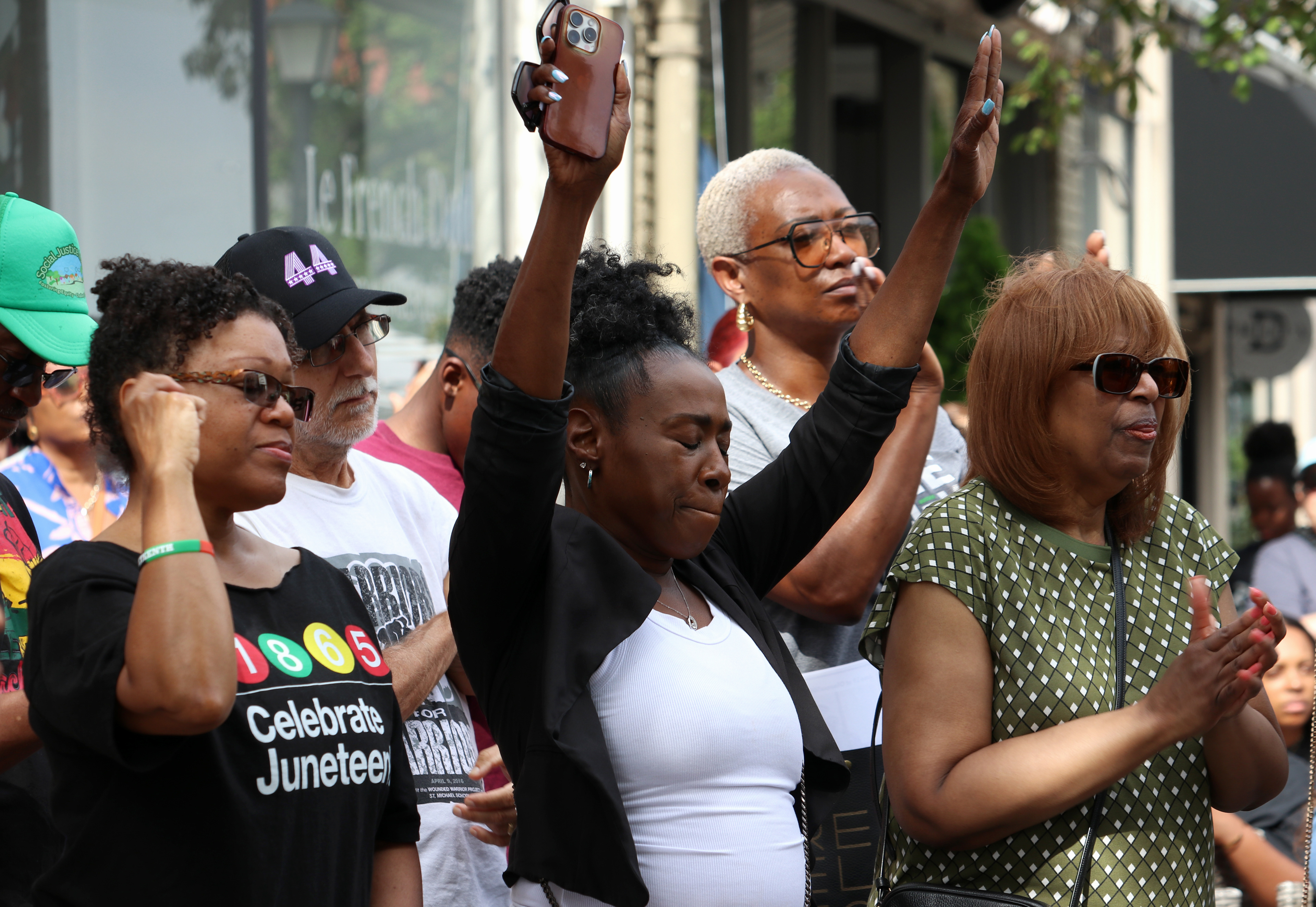 MONTCLAIR, NJ 06/19/2026 JUNETEENTH FLAG RAISING: A woman raises her hands in the air in support of Larry Hamm’s speech on Bloomfield Ave in Montclair. Photo by Sunah Choudhry.