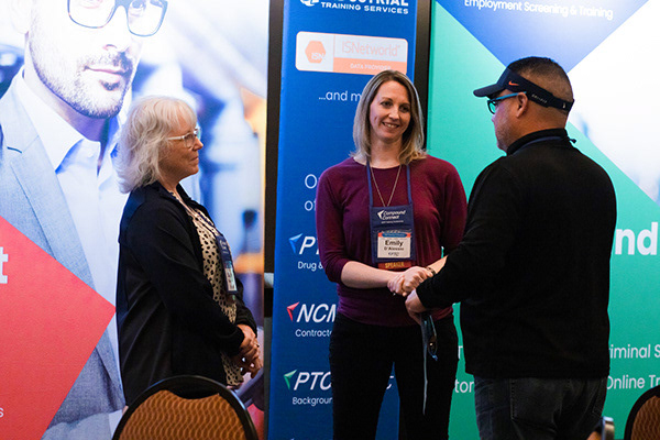 Talking to an attendee in front of the trade show displays created for additional marketing at the conference.