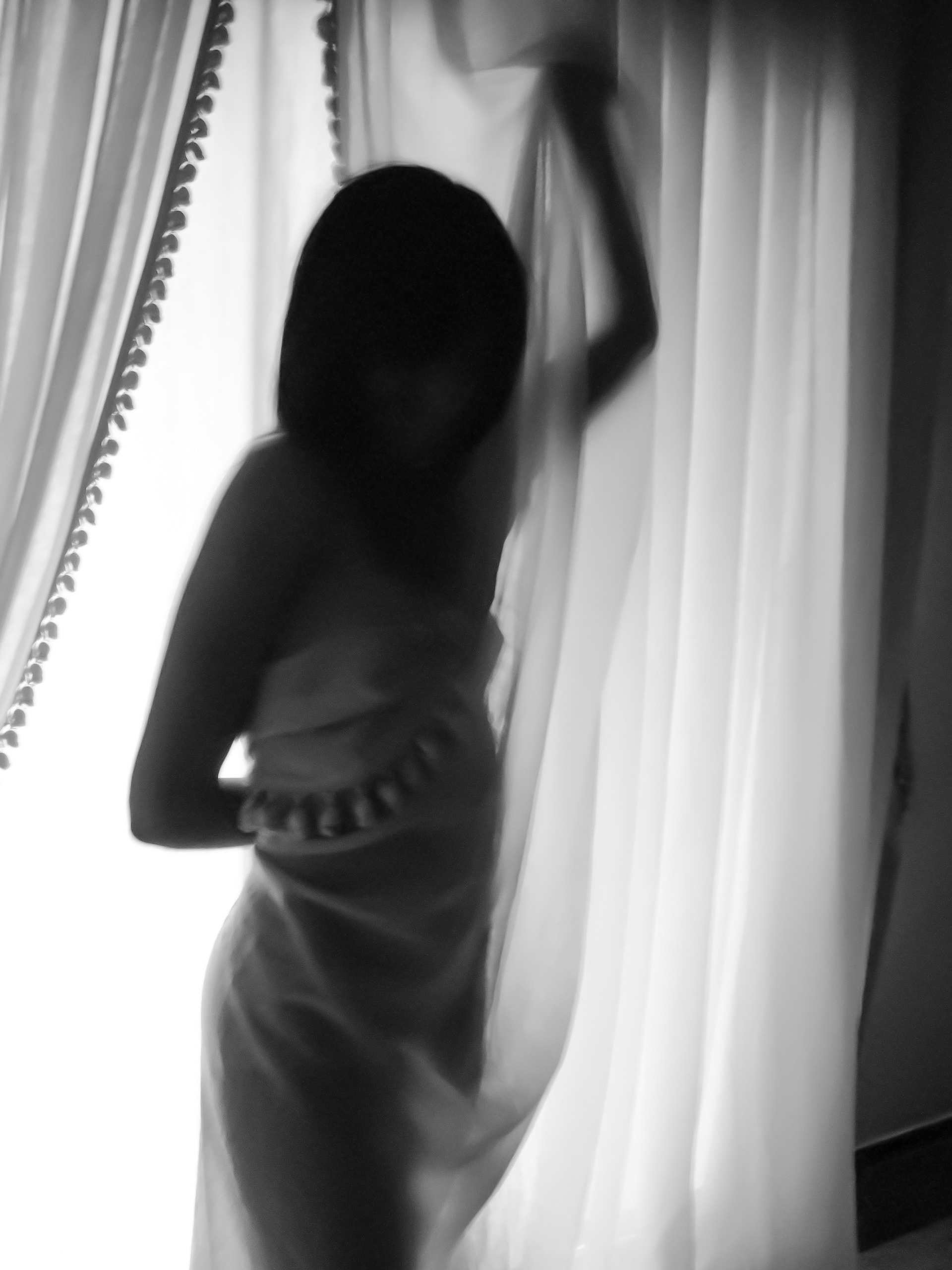 Une femme nue qui s'enroule dans les rideaux