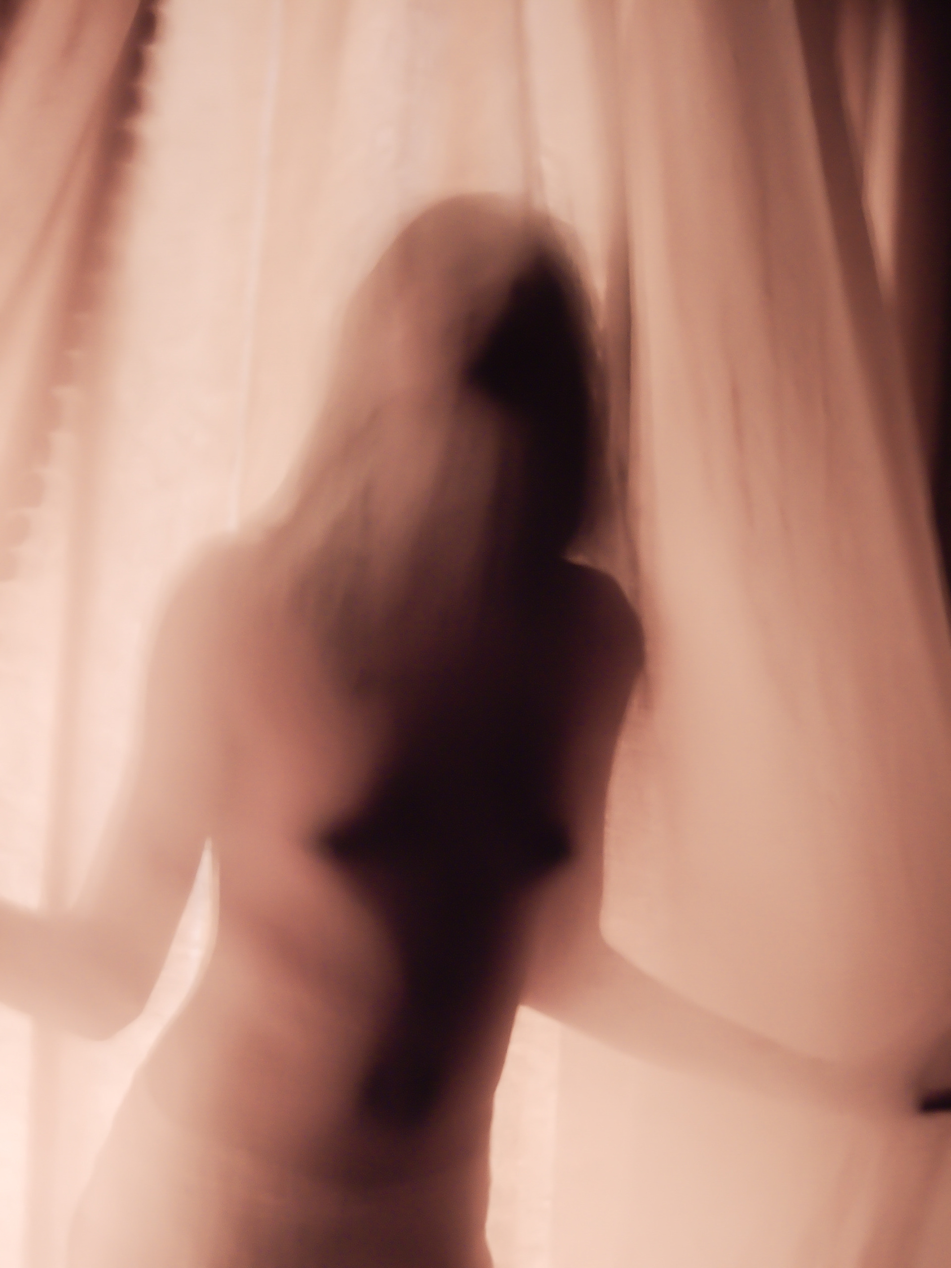 Femme torse nu derrière un voilage