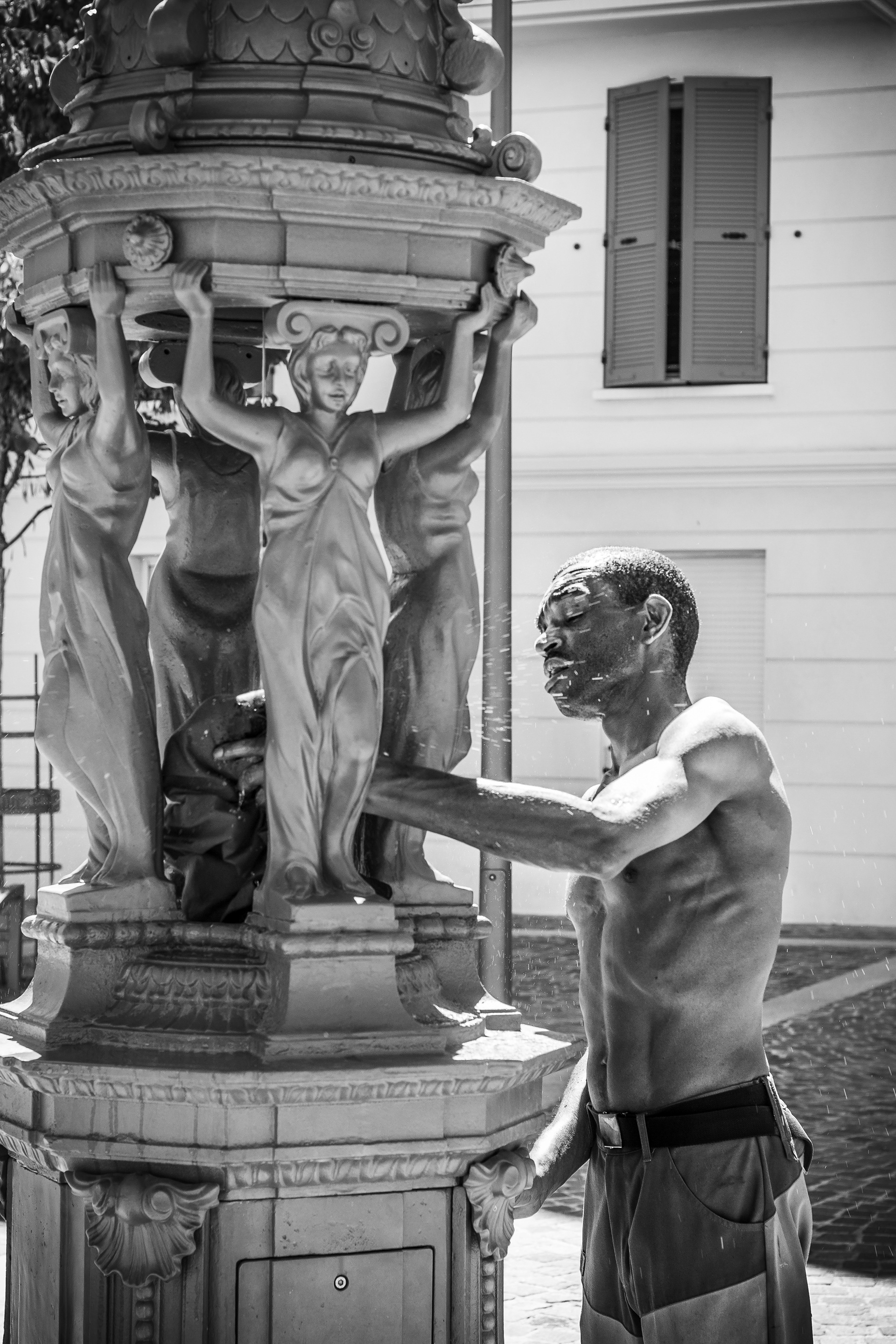Un homme qui se rafraichit dans une fontaine