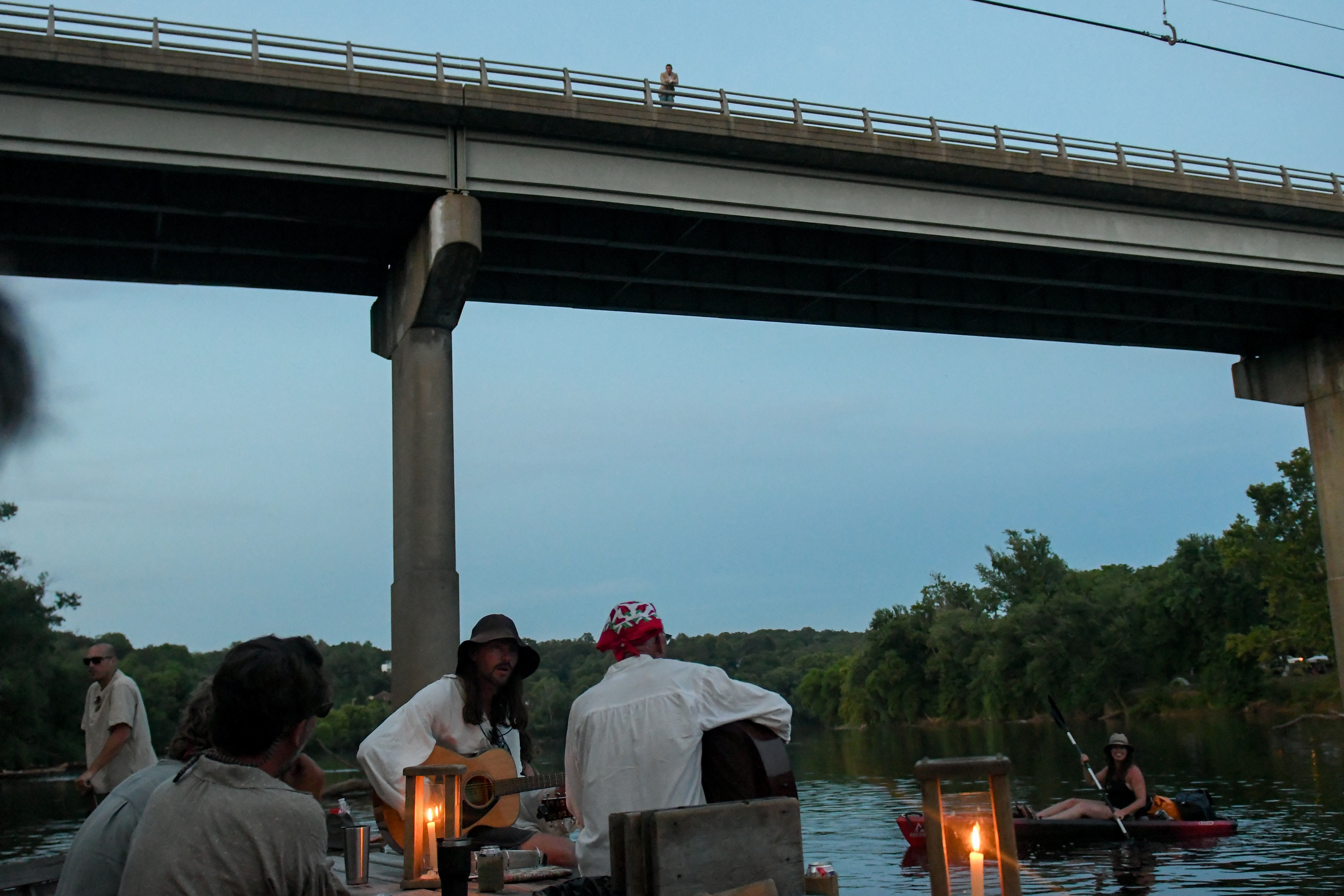 The batteau Morning Dew, lit by wax candles, passes under the Scottsville Bridge, to end the fifth day of their voyage on the James River, on Wednesday, June 19, 2024. The festival camps on private farms every night of their nine-day journey, with some also sleeping on their batteaux.