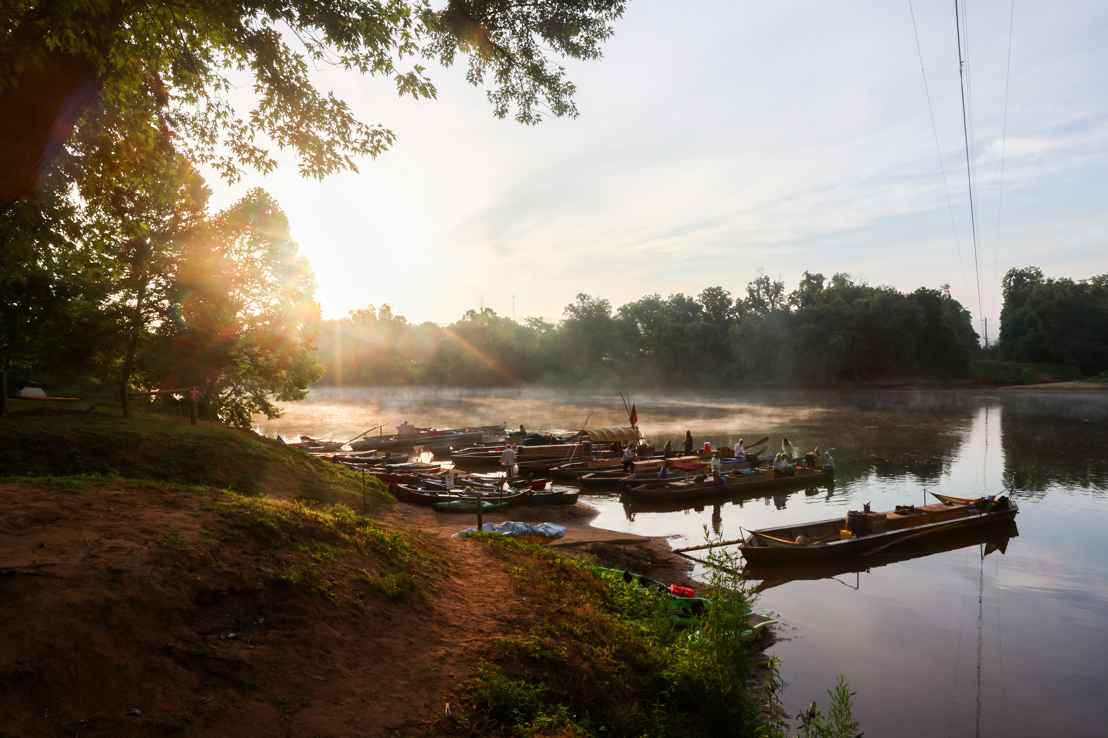 Batteaux of the James River Batteau Festival rest in the river at Howardsville's boat ramp on Wednesday, June 19, 2024, as the various crews prepare to depart on their journey to Scottsville. Final preparations include dumping out excess boat water, fixing seams, and buying ice and other supplies from local stores.