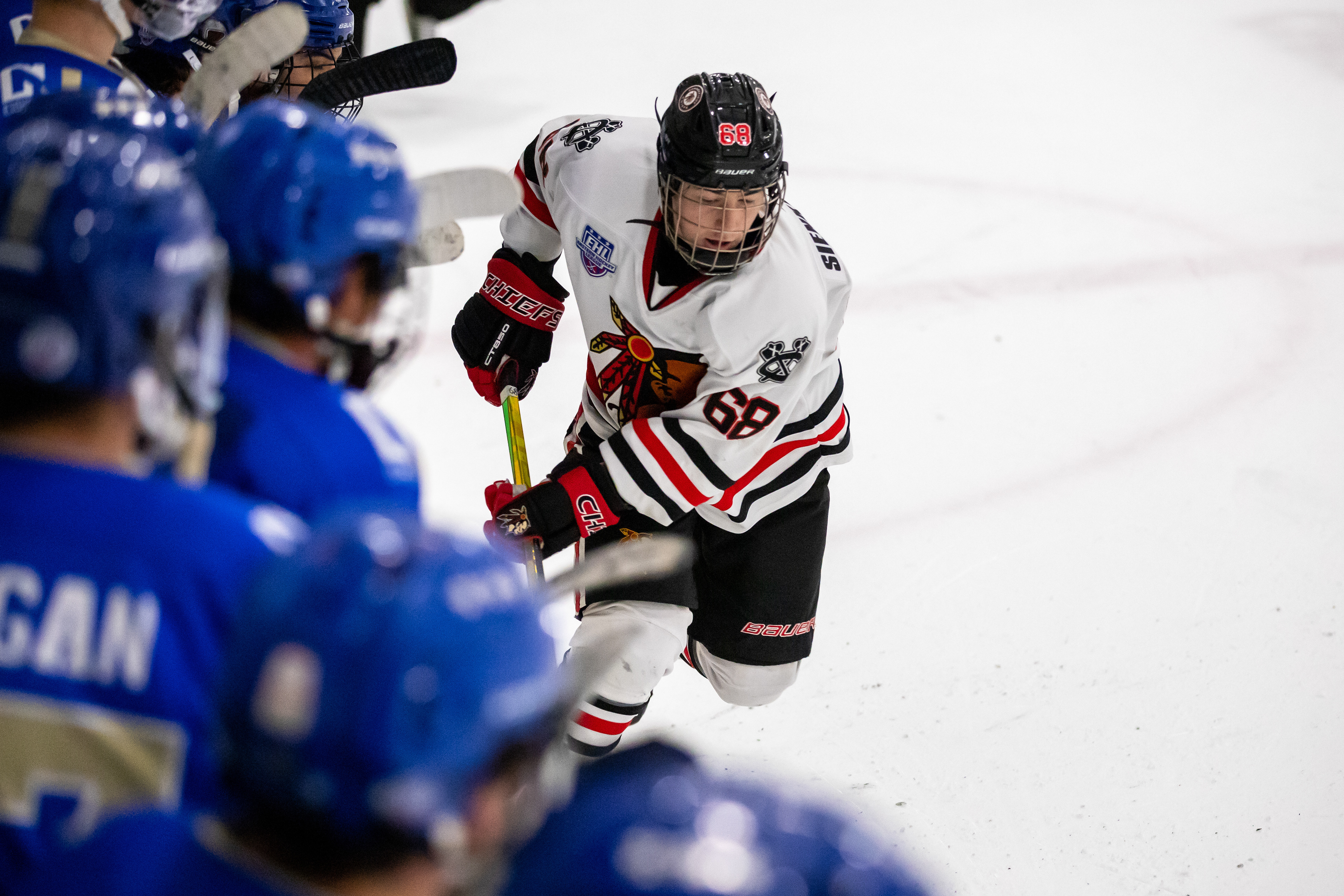 Filip Sienkiewicz carries the puck into the offensive zone as the opposing bench looks on.