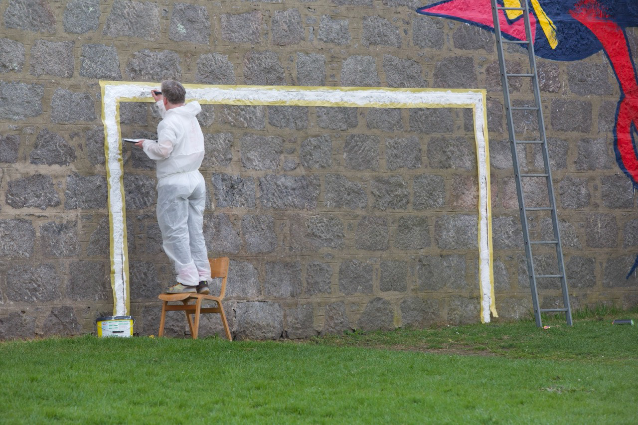 Colin from Fine Day Studios painting the goal post — a small but symbolic detail bringing the mural to life.