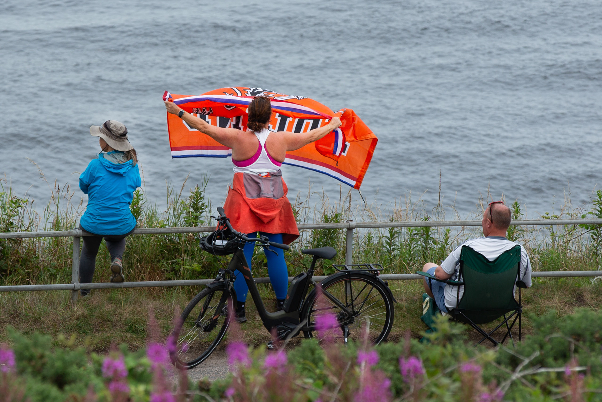 A dutch woman ways her flag to a passing ship