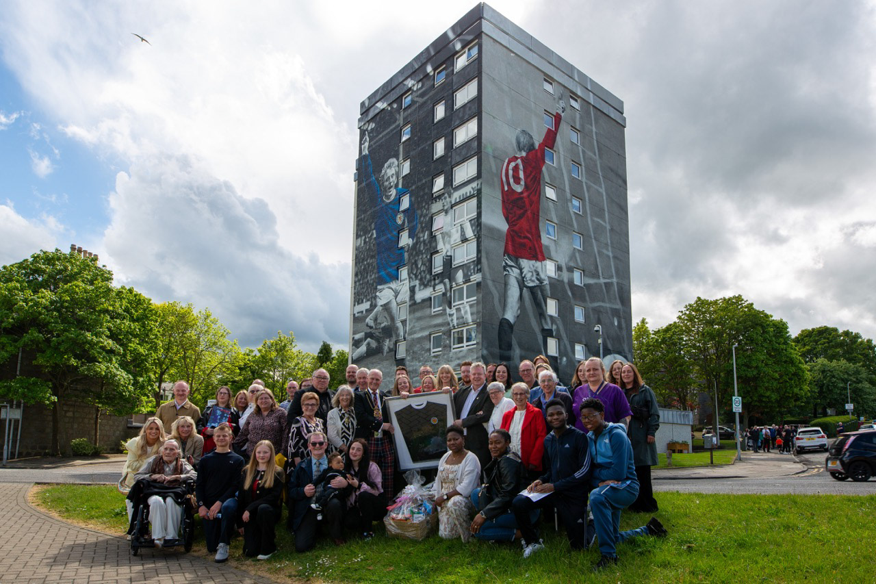 Clifton Court residents, carers, and 21 members of the Law family come together — a shared moment of pride, care, and connection at the heart of Printfield, reflecting the community spirit behind the Denis Law Legacy Trail.