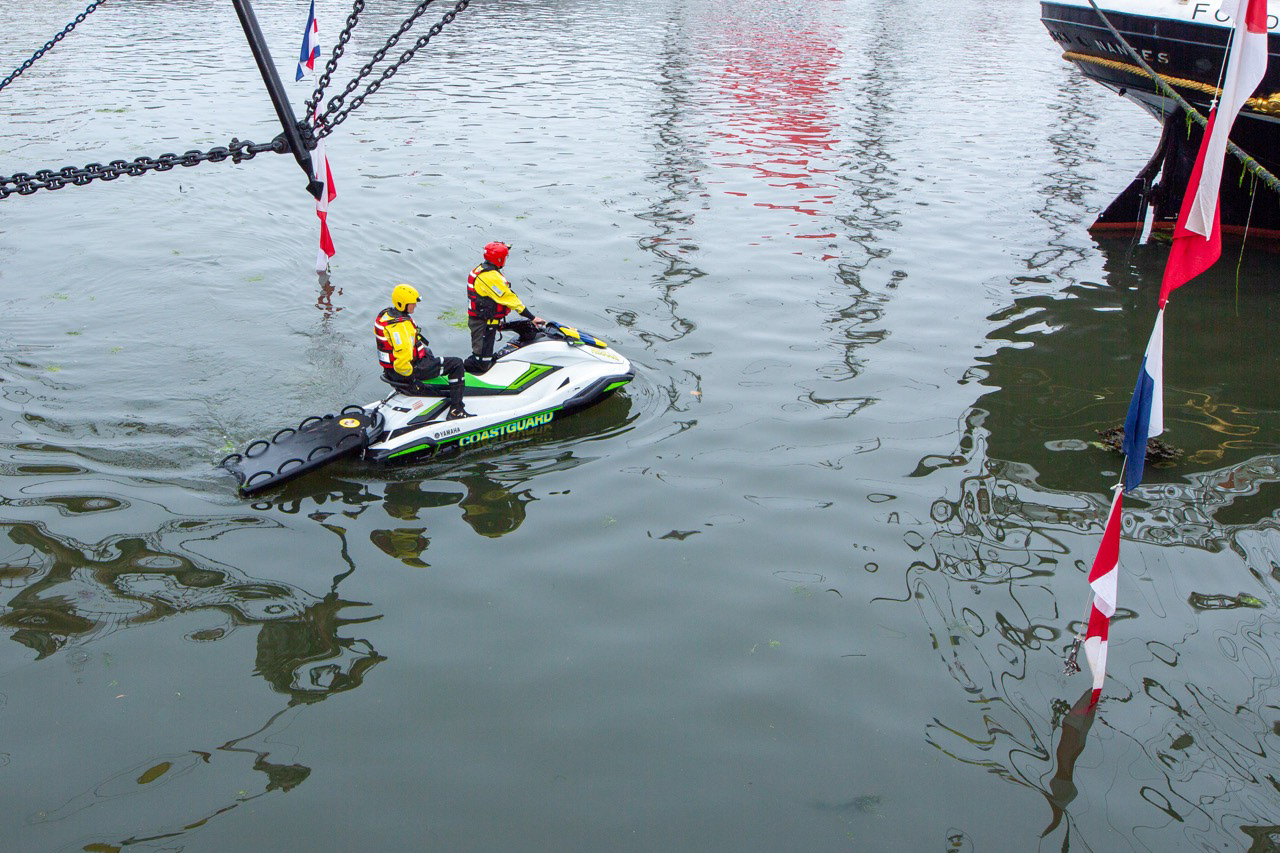 A Coast Guard fast rescue boat cuts across the harbour, alert, agile, and always on watc