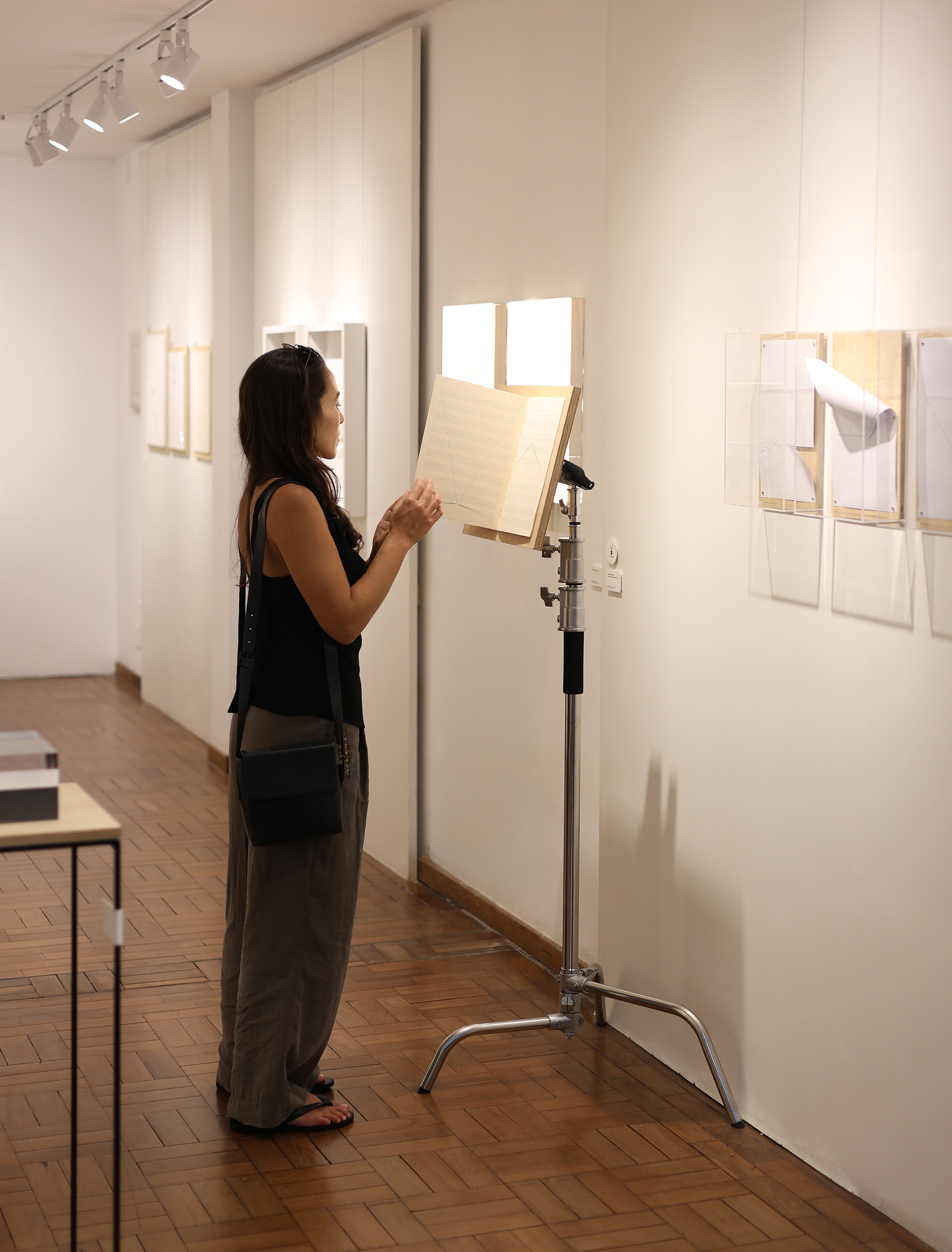 Registro da Obra Camas Silenciosas para Palavras em Suspensão, de Zans, Impressão digital sobre papel pólen, madeira e tripé metálico. 42 × 29,7 cm (publicação), 2025. Durante a mostra individual homônima.