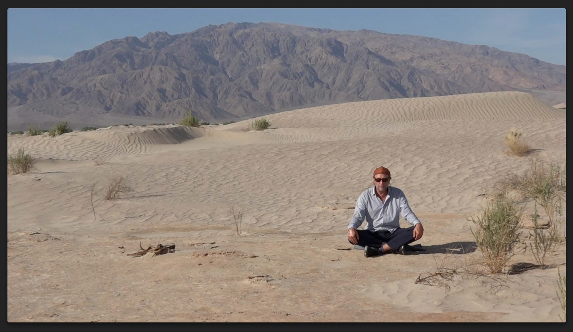 Still image of Alex Nowitz performing ‚Timbisha—A song from the desert‘ in the sand dunes of the Death Valley, California documented by Sabine Vogel during their artist residency at the Villa Aurora, Los Angeles (2022)