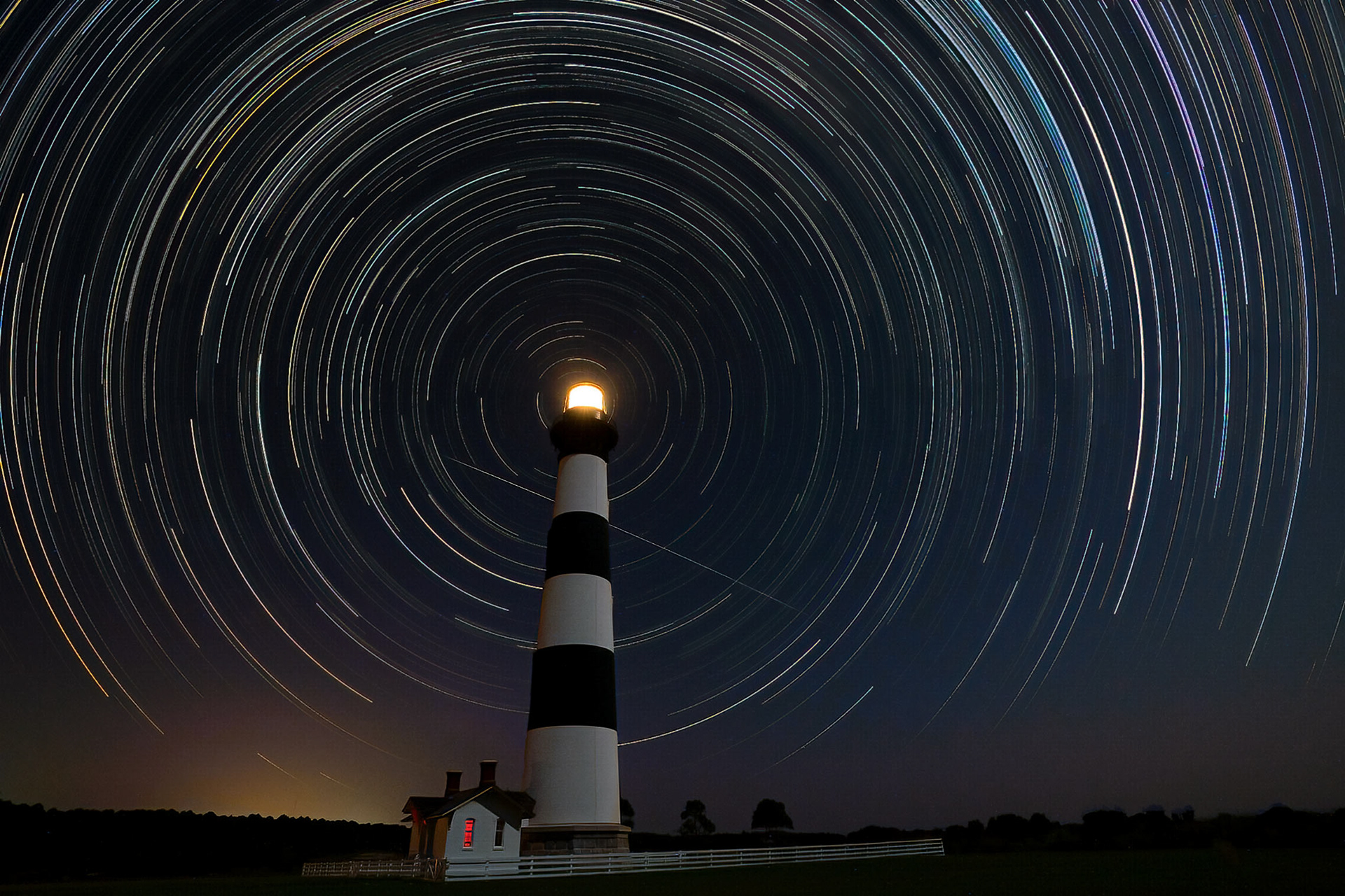 Star trails encircle the lighthouse on Bodie Island in the Outer Banks. A satellite can be seen streaking through the center of the star trails. The moon was nearly full, overpowering the dimmer stars and creating a more sparse collection of star trails. (Nags Head, NC)