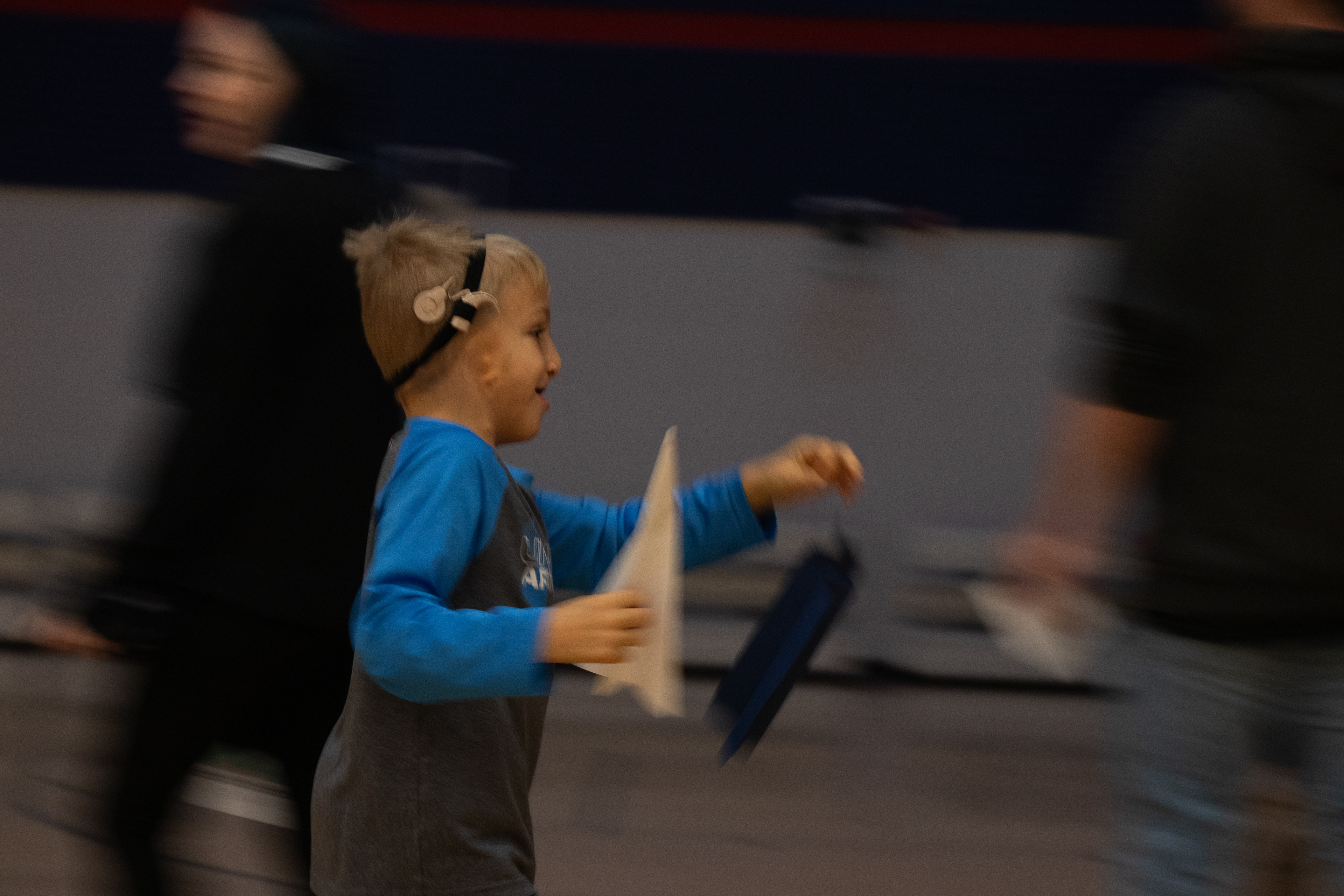 Nile, 7 of Iowa City, holds his paper airplane while running in the Scanlon Gym during the UI Day of Play event at Mercer Aquatic Center, Iowa City, IA Saturday, Nov. 16, 2024. Nile runs back to the start of the station to throw his airplane again. (SJMC/ Sierra Christensen)