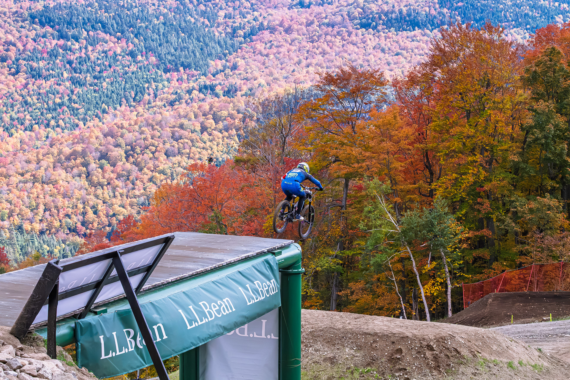 2026 UCI Downhill World Cup Rider Airborne Amidst Beautiful Fall Colors Backdrop