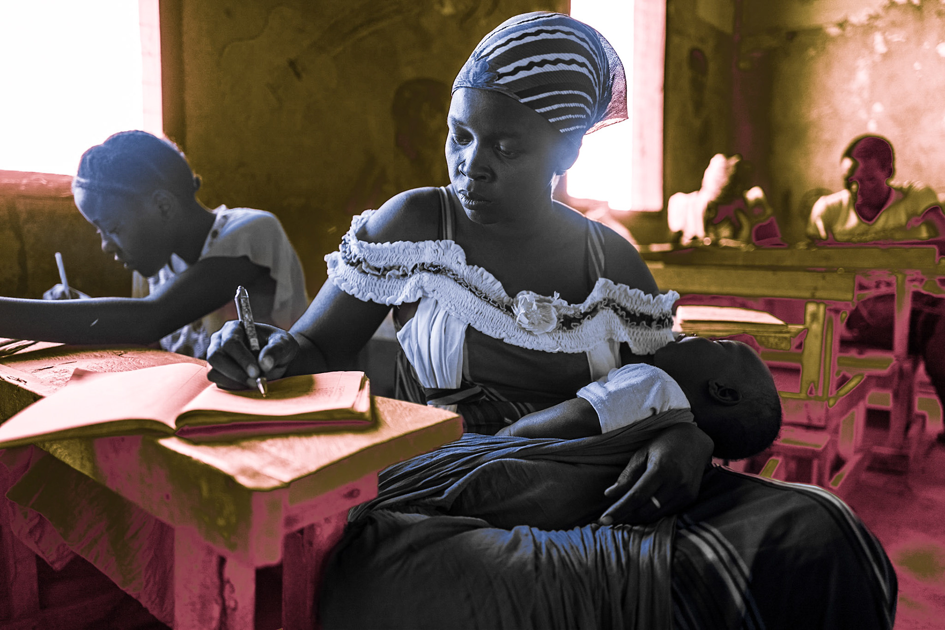 A mother holds her baby while studying in a classroom in  Kakuma refugee camp. The camp has 52 schools offering early childhood, primary, and secondary education. Some of the teachers at the camp are refugees themselves.