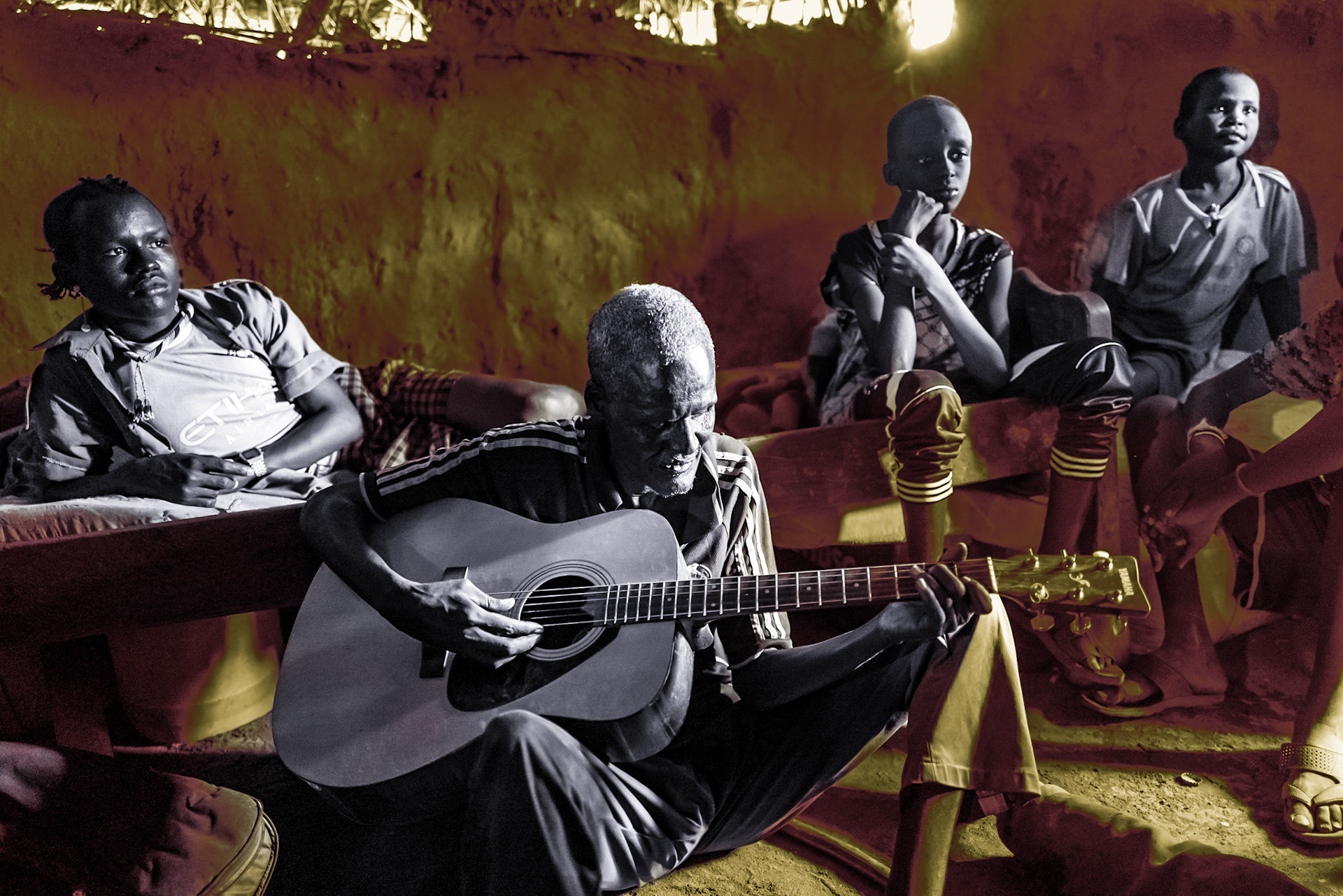 A man is playing a local song in a traditional mud hut in Selicho. While being blind by birth, he learned how to play the guitar in the local church. As the region develops, many indigenous groups like the Daasanach are adopting a more western lifestyle.