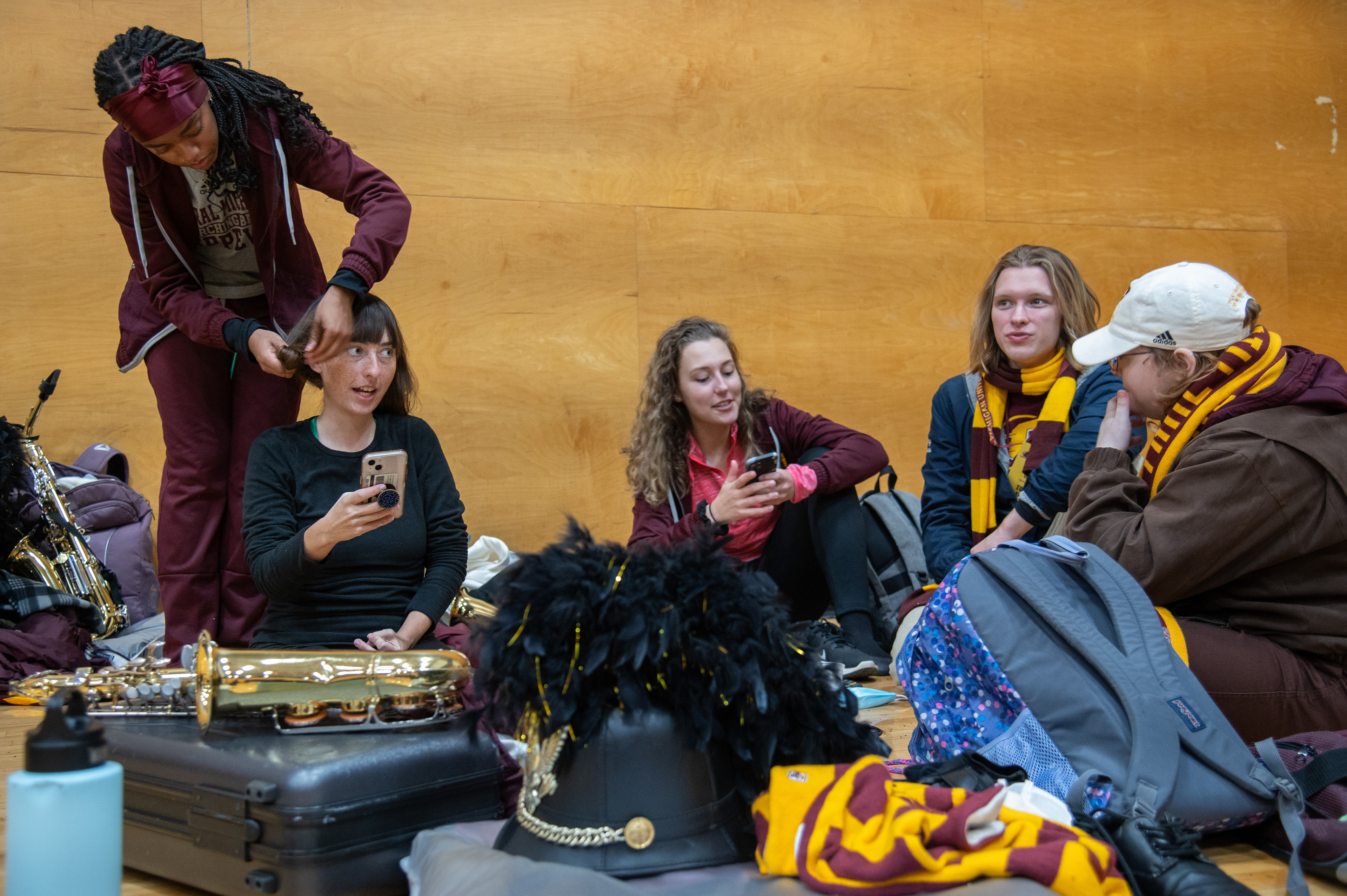 Ariah Bremby, far left, braids Gaia’s hair while getting ready for Central Michigan’s football game in the Student Activity Center, on the campus of Central Michigan University, Mount Pleasant, Michigan, Tuesday, October 31, 2023. Halftime rehearsal ended earlier than planned, so there was extra time to get ready for the game.