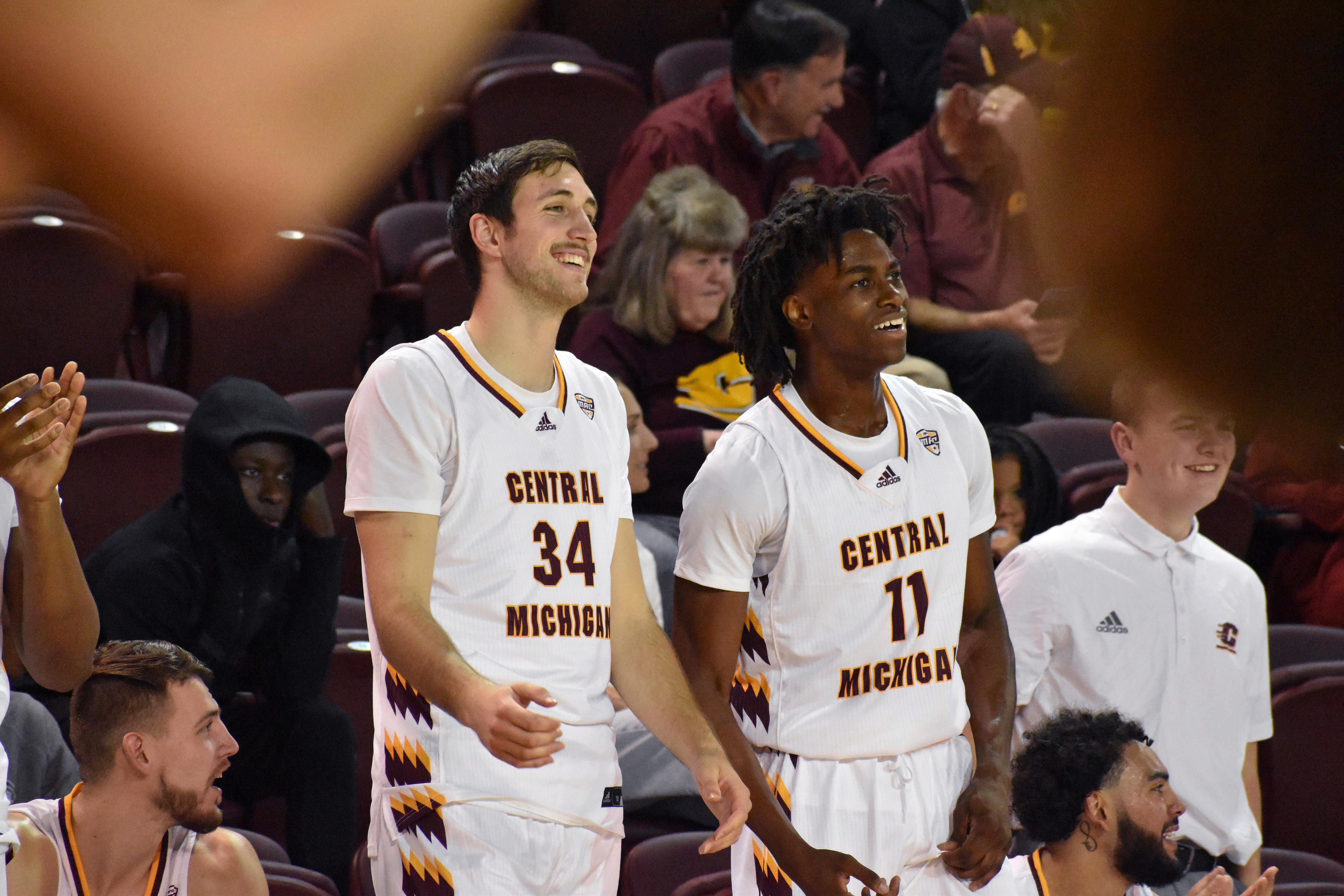 (From left) Junior forward Caleb Hodgson and freshman forward Ola Ajiboye smile on the sideline after a teammate scored during CMU's exhibition game against Northwood Thursday, Nov. 3 in McGuirk Arena.