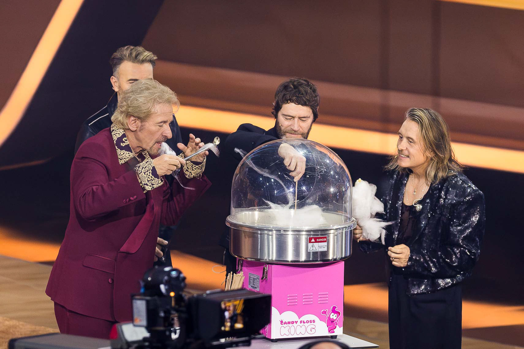 Thomas Gottschalk (73) mit Gary Barlow (52), Howard Paul Donald (55) und Mark Anthony Patrick Owen (51) von Take That beim Zuckerwatte herstellen