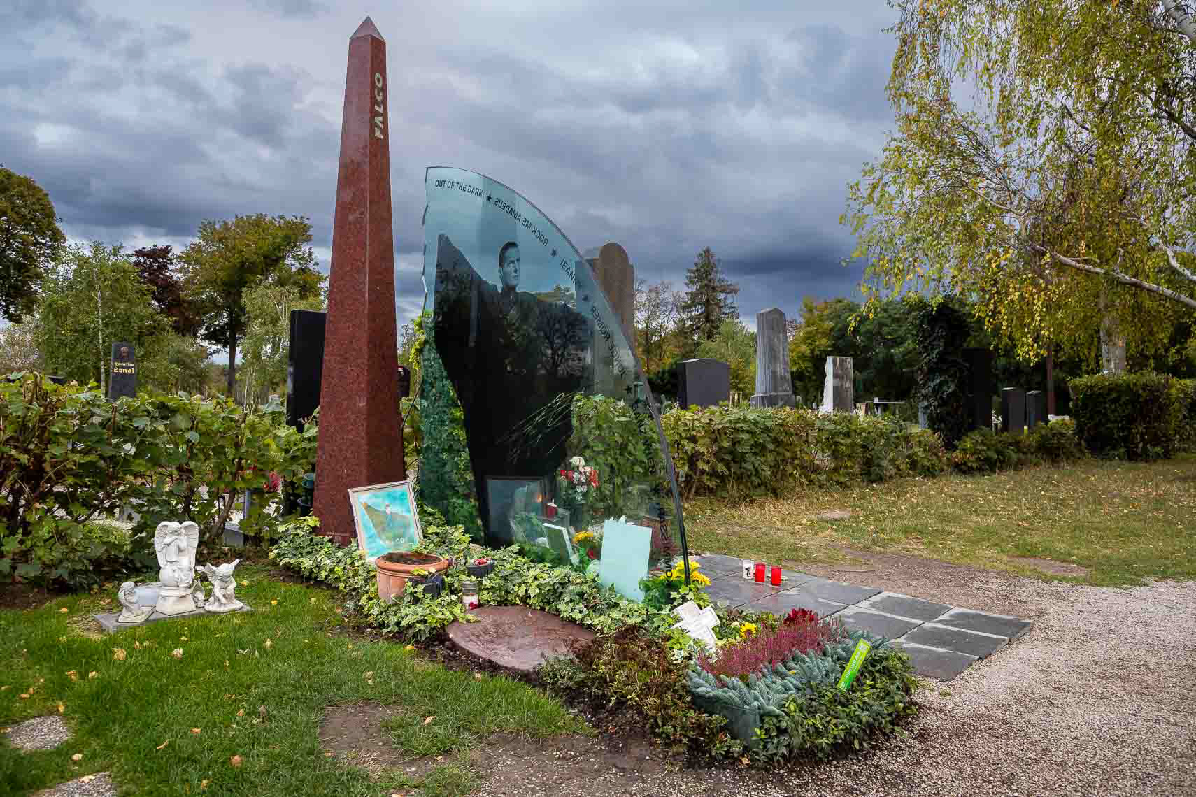 Ehrengrab von Musiker Hans Hölzel alias Falco (1957 - 1998) in Gruppe 40, Nr. 64 auf dem Zentralfriedhof Wien. Beigesetzt wurde er unter anderem in einem Versace-Hemd, zu den Klängen des 1985 von ihm gesungenen Bob-Dylan-Songs „It's All Over Now, Baby Blue". Falcos Sarg trugen jene Wiener Motorrad-Rocker, die 1985 im Video "Rock me Amadeus" mitgespielt hatten. Darauf lag der Mantel, den er in diesem Video getragen hatte. Tausende Menschen kamen zum Begräbnis. Die Idee, der Entwurf, die Planung und auch die Ausführung der steinernen Teile des Falco-Grabmales stammen von Erwin Zechmeister, Steinmetz in Hollabrunn. Die Glasplatte aus Panzerglas wurde in Tschechien hergestellt. Finanziert wurde das Grabmal von Falcos Freund, dem Geschäftsmann Ronald Seunig (Excalibur City). Kostenpunkt umgerechnet ca. 20 000 Euro. Die Aufstellung erfolgte 1999. Das Grabmal besteht aus drei Teilen: Falco - der Künstler (Obelisk), Falco - das Werk (Glasplatte), Falco - der Mensch (Säule). Neben dem Grab befindet sich eine Sitzbank für die Pilger, die neben ihm vorgesehenen letzten Ruhestätten werden nicht mehr belegt werden.