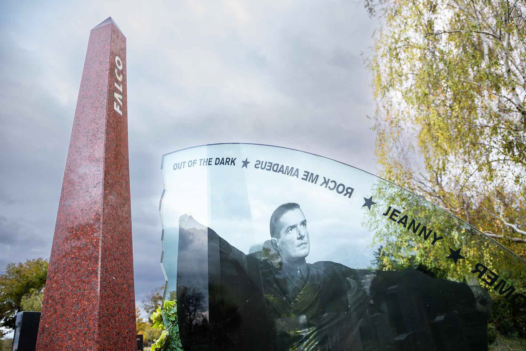 Ehrengrab von Musiker Hans Hölzel alias Falco (1957 - 1998) in Gruppe 40, Nr. 64 auf dem Zentralfriedhof Wien. Beigesetzt wurde er unter anderem in einem Versace-Hemd, zu den Klängen des 1985 von ihm gesungenen Bob-Dylan-Songs „It's All Over Now, Baby Blue". Falcos Sarg trugen jene Wiener Motorrad-Rocker, die 1985 im Video "Rock me Amadeus" mitgespielt hatten. Darauf lag der Mantel, den er in diesem Video getragen hatte. Tausende Menschen kamen zum Begräbnis. Die Idee, der Entwurf, die Planung und auch die Ausführung der steinernen Teile des Falco-Grabmales stammen von Erwin Zechmeister, Steinmetz in Hollabrunn. Die Glasplatte aus Panzerglas wurde in Tschechien hergestellt. Finanziert wurde das Grabmal von Falcos Freund, dem Geschäftsmann Ronald Seunig (Excalibur City). Kostenpunkt umgerechnet ca. 20 000 Euro. Die Aufstellung erfolgte 1999. Das Grabmal besteht aus drei Teilen: Falco - der Künstler (Obelisk), Falco - das Werk (Glasplatte), Falco - der Mensch (Säule). Neben dem Grab befindet sich eine Sitzbank für die Pilger, die neben ihm vorgesehenen letzten Ruhestätten werden nicht mehr belegt werden.