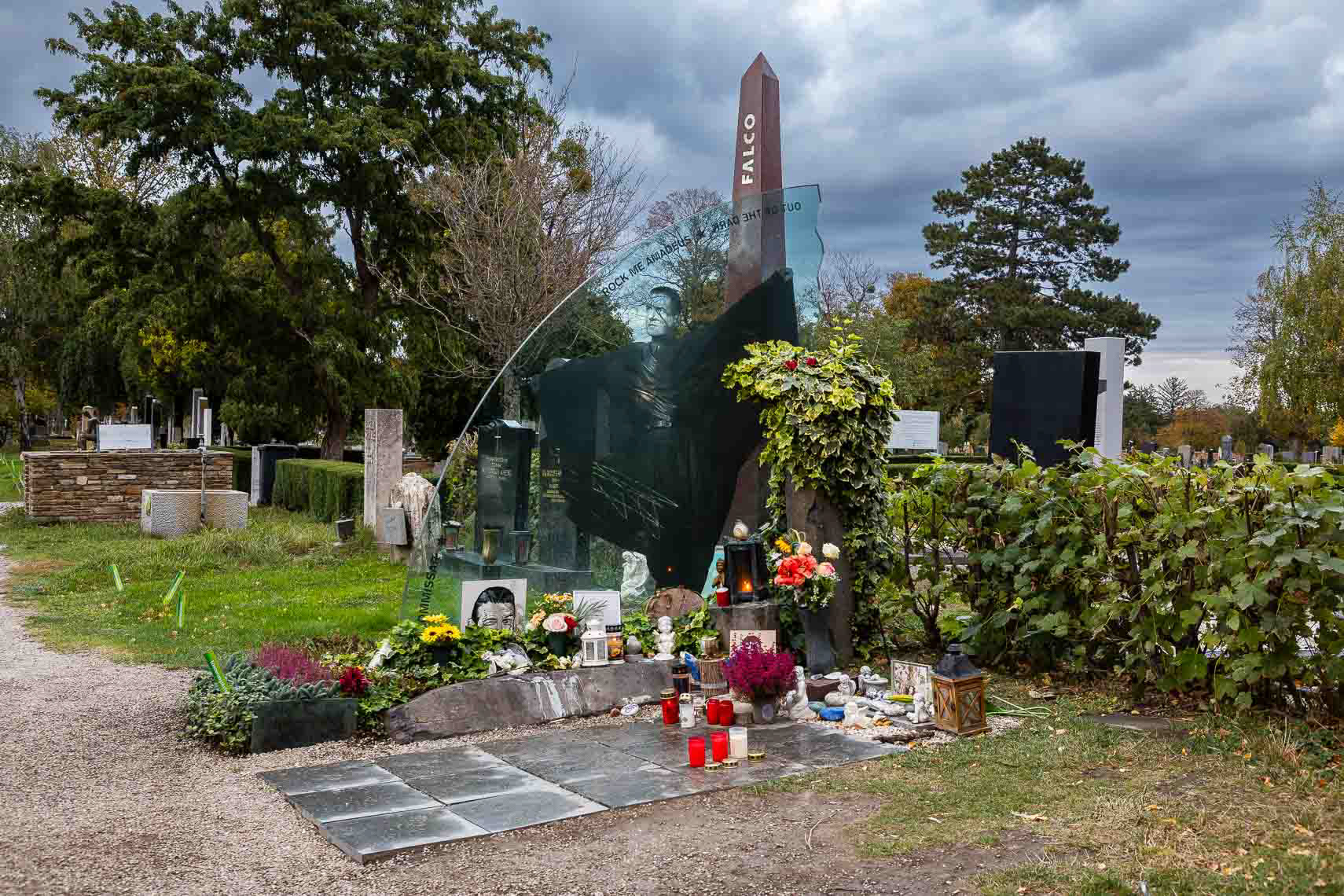 Ehrengrab von Musiker Hans Hölzel alias Falco (1957 - 1998) in Gruppe 40, Nr. 64 auf dem Zentralfriedhof Wien. Beigesetzt wurde er unter anderem in einem Versace-Hemd, zu den Klängen des 1985 von ihm gesungenen Bob-Dylan-Songs „It's All Over Now, Baby Blue". Falcos Sarg trugen jene Wiener Motorrad-Rocker, die 1985 im Video "Rock me Amadeus" mitgespielt hatten. Darauf lag der Mantel, den er in diesem Video getragen hatte. Tausende Menschen kamen zum Begräbnis. Die Idee, der Entwurf, die Planung und auch die Ausführung der steinernen Teile des Falco-Grabmales stammen von Erwin Zechmeister, Steinmetz in Hollabrunn. Die Glasplatte aus Panzerglas wurde in Tschechien hergestellt. Finanziert wurde das Grabmal von Falcos Freund, dem Geschäftsmann Ronald Seunig (Excalibur City). Kostenpunkt umgerechnet ca. 20 000 Euro. Die Aufstellung erfolgte 1999. Das Grabmal besteht aus drei Teilen: Falco - der Künstler (Obelisk), Falco - das Werk (Glasplatte), Falco - der Mensch (Säule). Neben dem Grab befindet sich eine Sitzbank für die Pilger, die neben ihm vorgesehenen letzten Ruhestätten werden nicht mehr belegt werden.