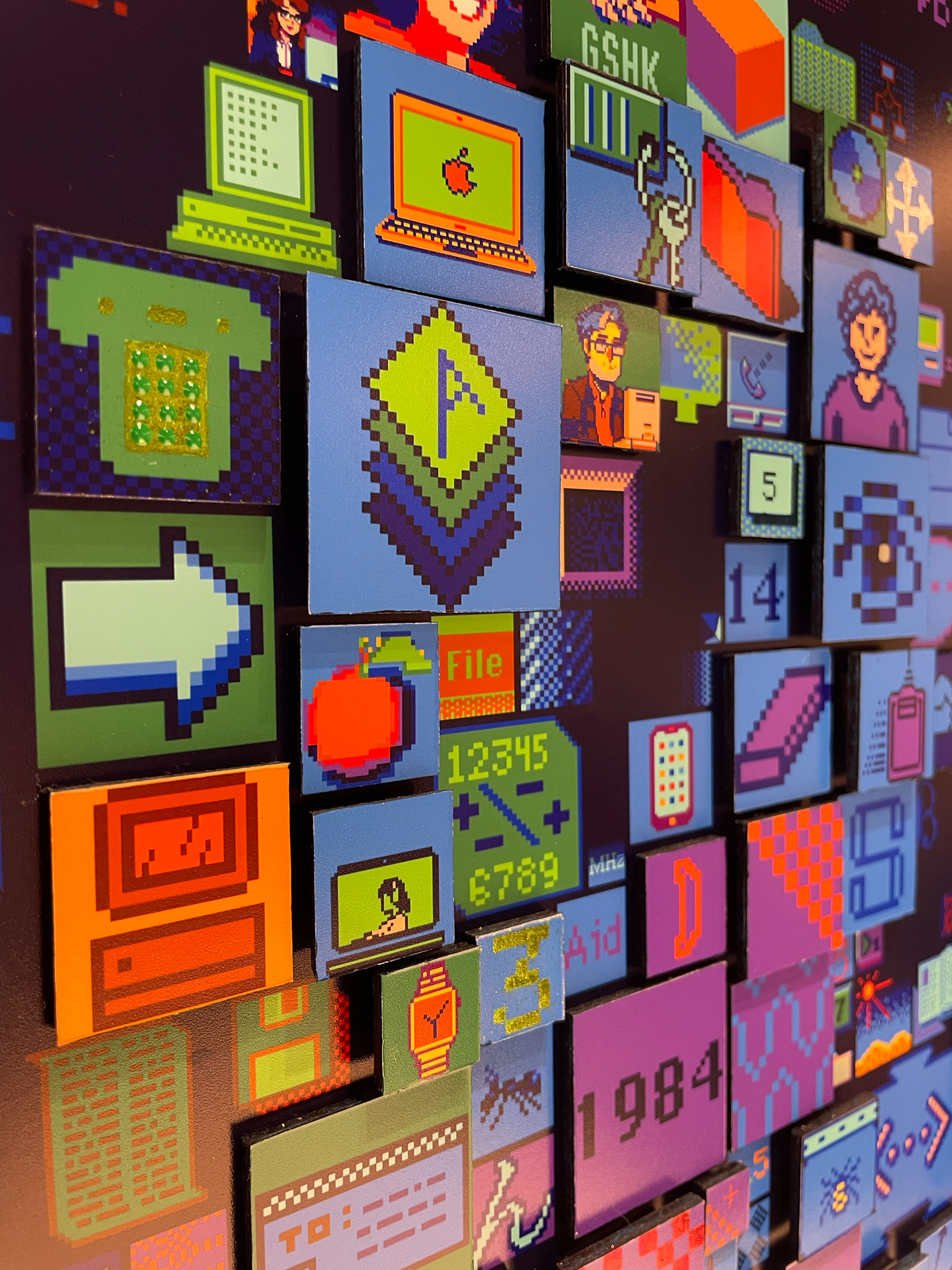 Detailed close-up of Charis Tsevis' digital mosaic "HELLO" artwork for Apple headquarters showing pixelated interface elements including Susan Kare's iconic designs, Macintosh interfaces, and modern digital symbols spanning four decades of Apple's history