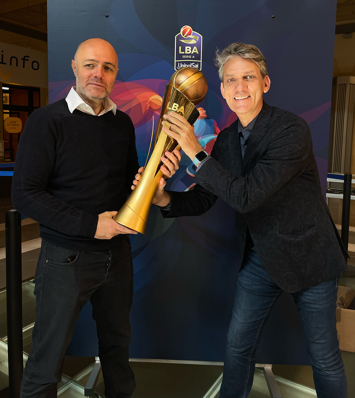 Paolo Guidobono, creative director of Foolbite, and Charis Tsevis pose with a golden trophy at the presentation of the Lega Basket Serie A season 2023-2024 in Bologna.