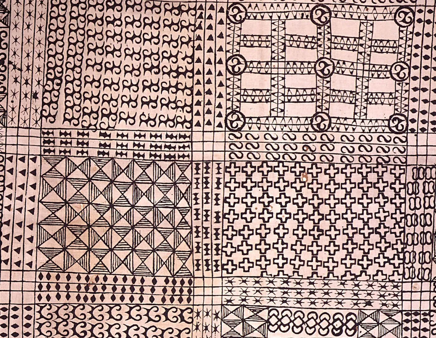 A close-up of Adinkra cloth, showcasing a detailed arrangement of black geometric symbols on a light background. The design includes repeating patterns such as triangles, squares, and interlocking shapes, each carrying symbolic meaning rooted in Ashanti and Baoulé culture. This piece exemplifies the artistry and cultural significance of Adinkra textiles.