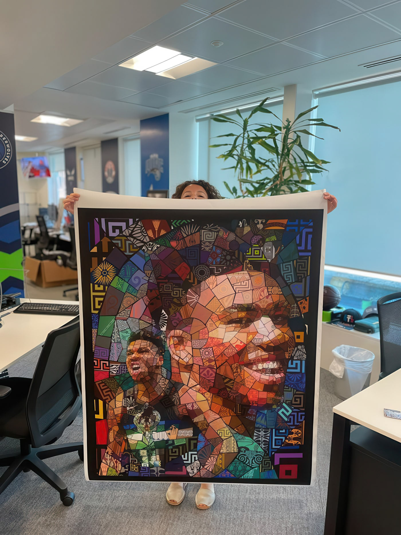 Sara Trombetta, Content Producer - EME for NBA, holding a vibrant mosaic portrait of Giannis Antetokounmpo created by Charis Tsevis for the NBA Creator Series.
