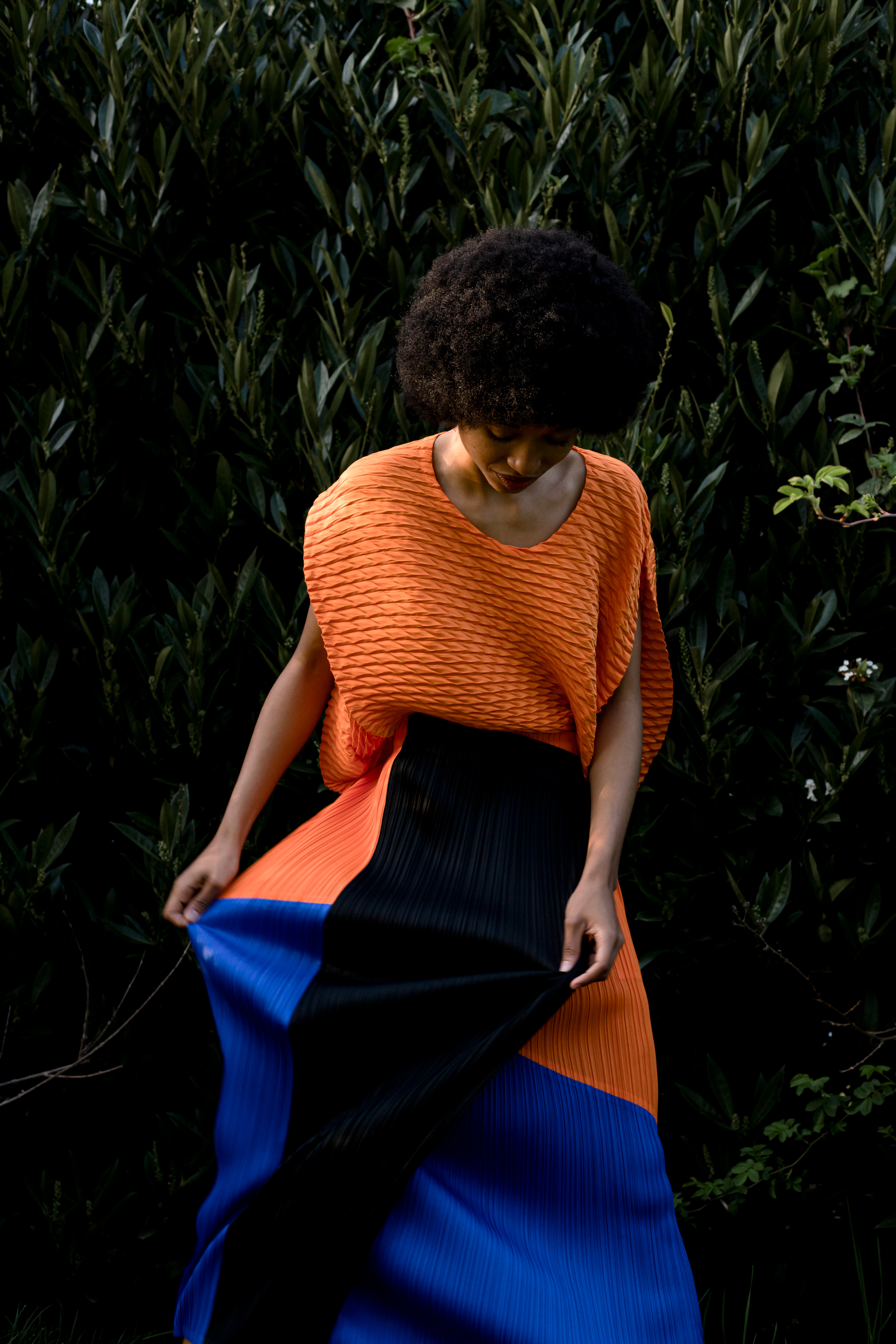 Jupe plissée tricolore en polyester Pleats Please Issey Miyake. Top orange en polyester Issey Miyake. © Aurélie Nydegger - Modèle Inès