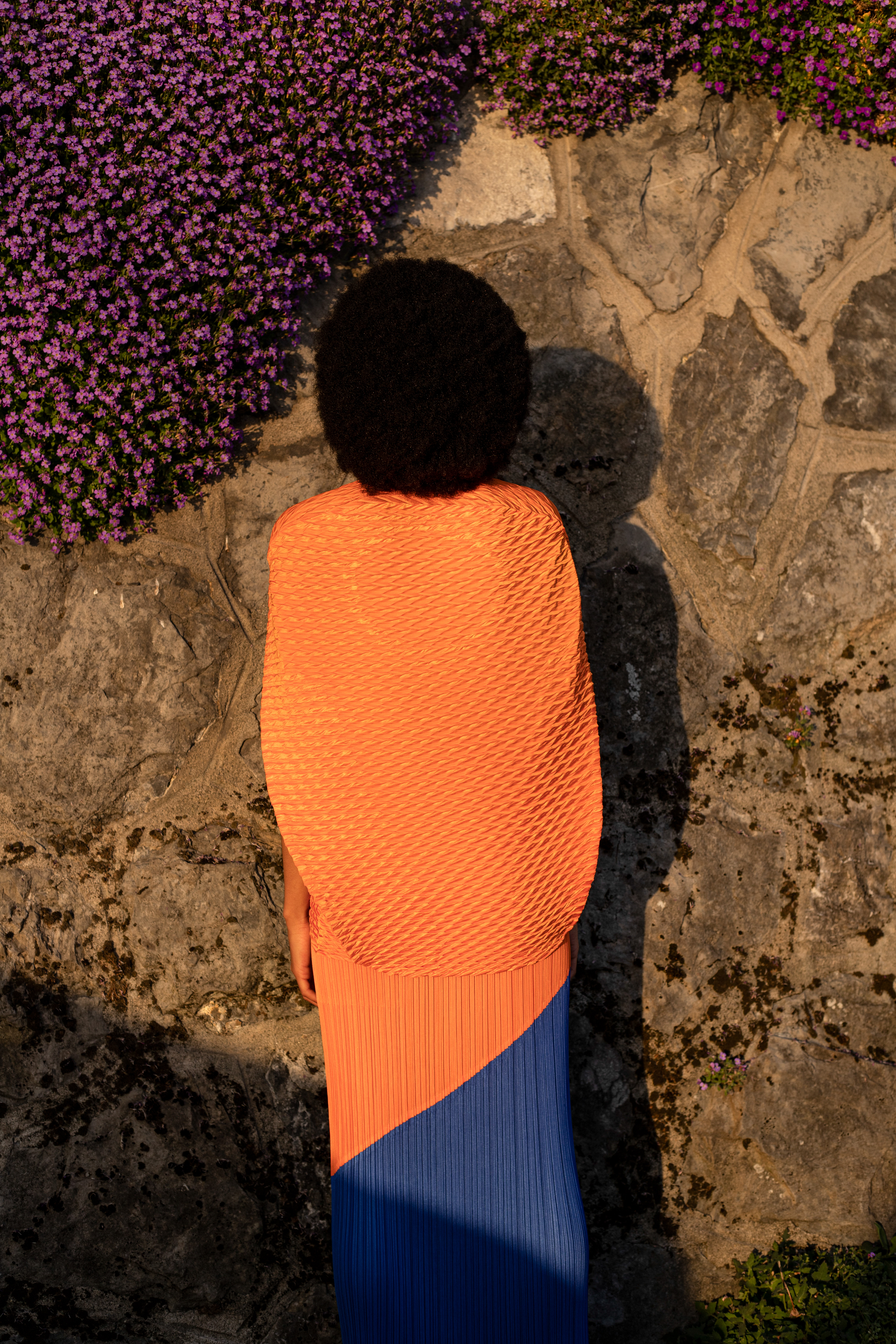 Jupe plissée tricolore en polyester Pleats Please Issey Miyake. Top orange en polyester Issey Miyake. © Aurélie Nydegger - Modèle Inès