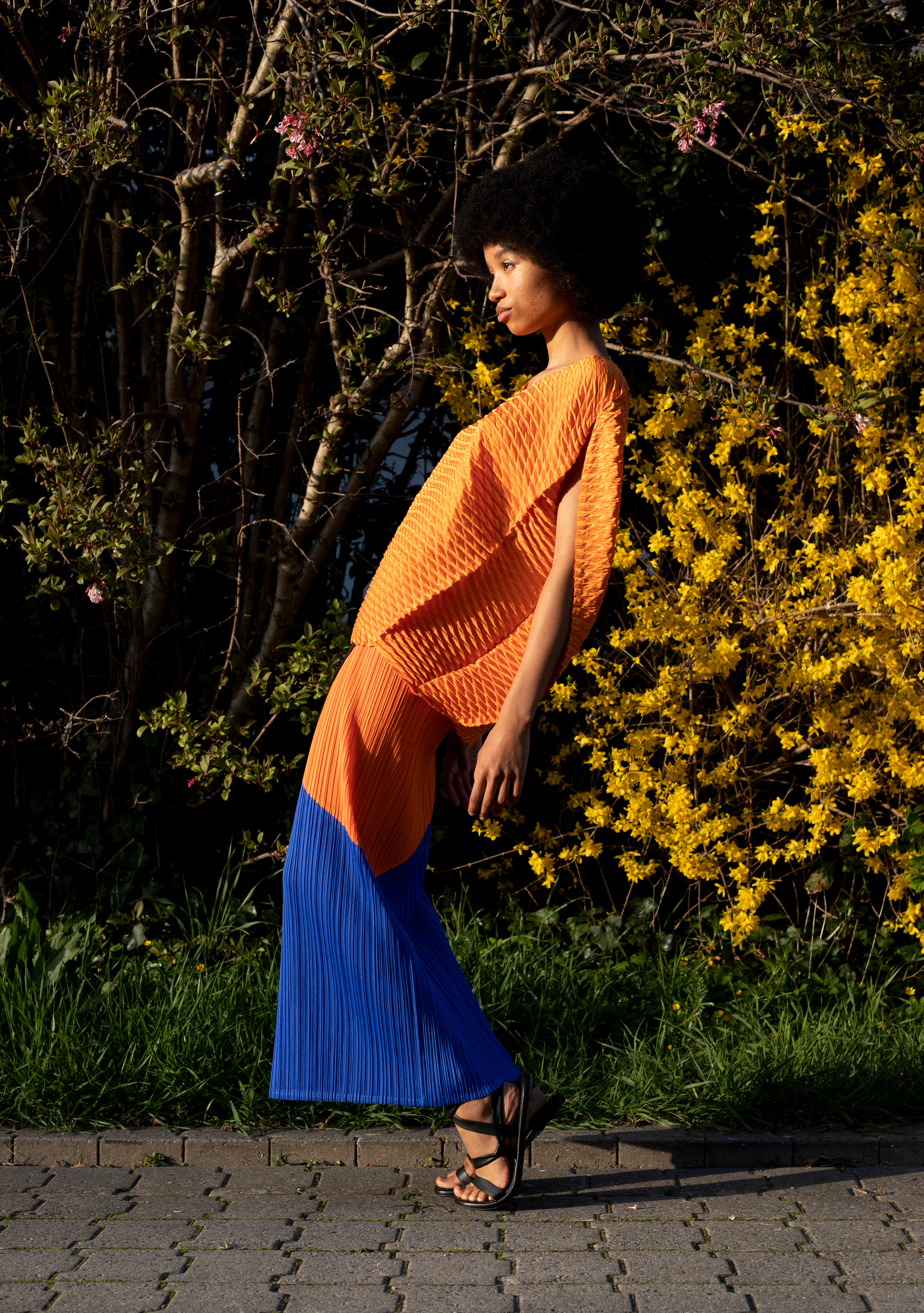 Jupe plissée tricolore en polyester Pleats Please Issey Miyake. Top orange en polyester Issey Miyake. © Aurélie Nydegger - Modèle Inès
