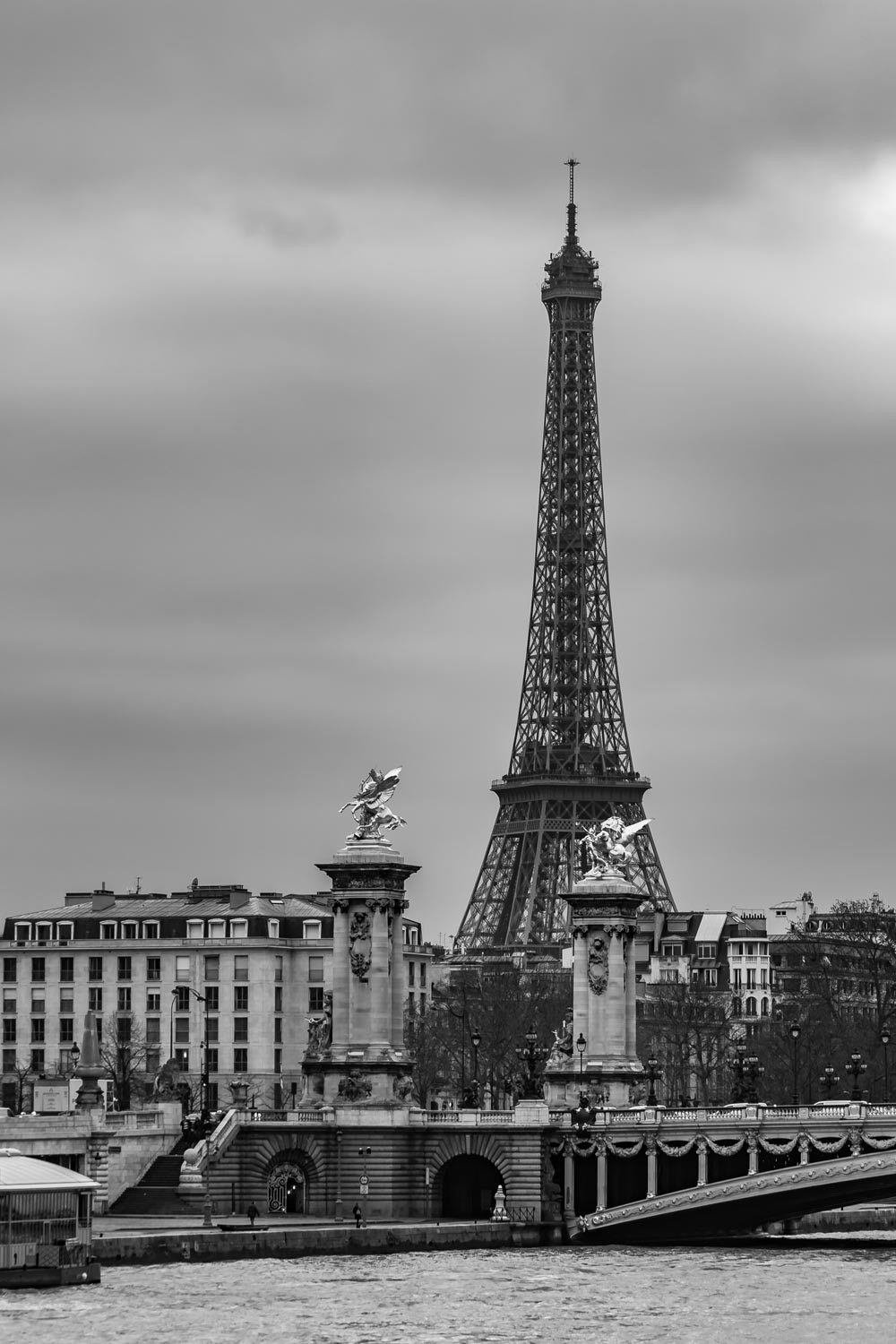 Moody cityscape with Pont Alexandre III bridge, Seine river and Eiffel Tower in Paris, France in black and white