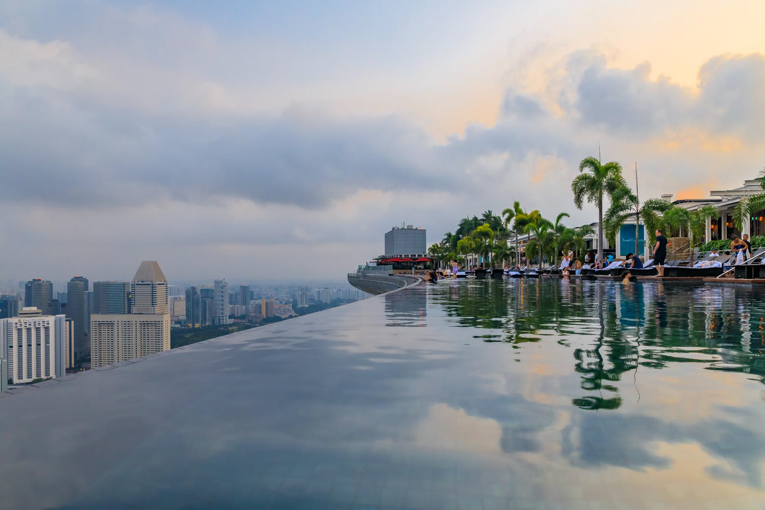 Famous infinity pool in the Marina Bay Sands luxury hotel and city skyline with skyscrapers at sunrise in Singapore