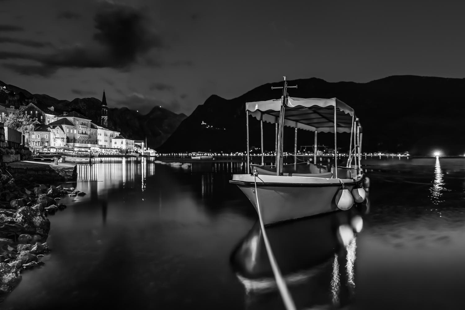 Sunset in Kotor Bay with a docked boat in the town of Perast, Montenegro, black and white