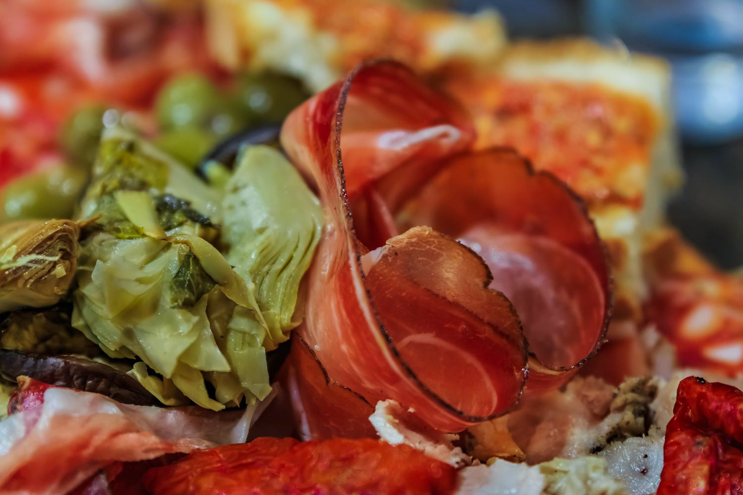 Antipasto platter with cured meats like prosciutto and salami; artichoke hearts, olives, and cheeses at a restaurant in Rome Italy
