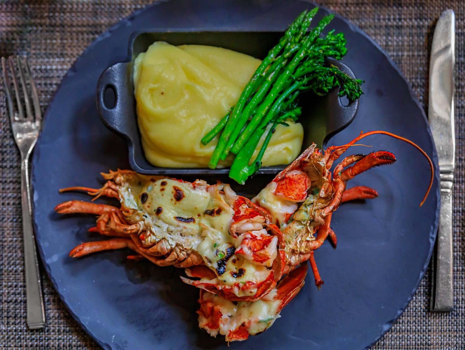 Whole grilled lobster on a plate at a luxury restaurant, with mashed potatoes and green asparagus in Vancouver, Canada