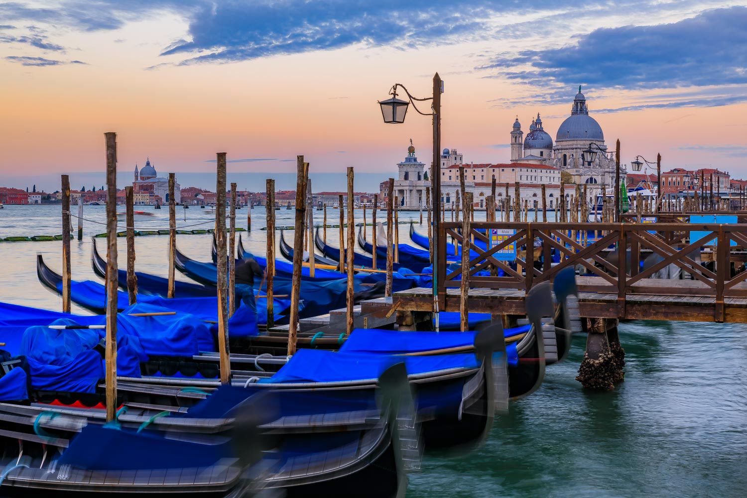 Gondolas along Grand Canal at St Marco square with Basilica of Santa Maria della Salute at sunrise in Venice Italy